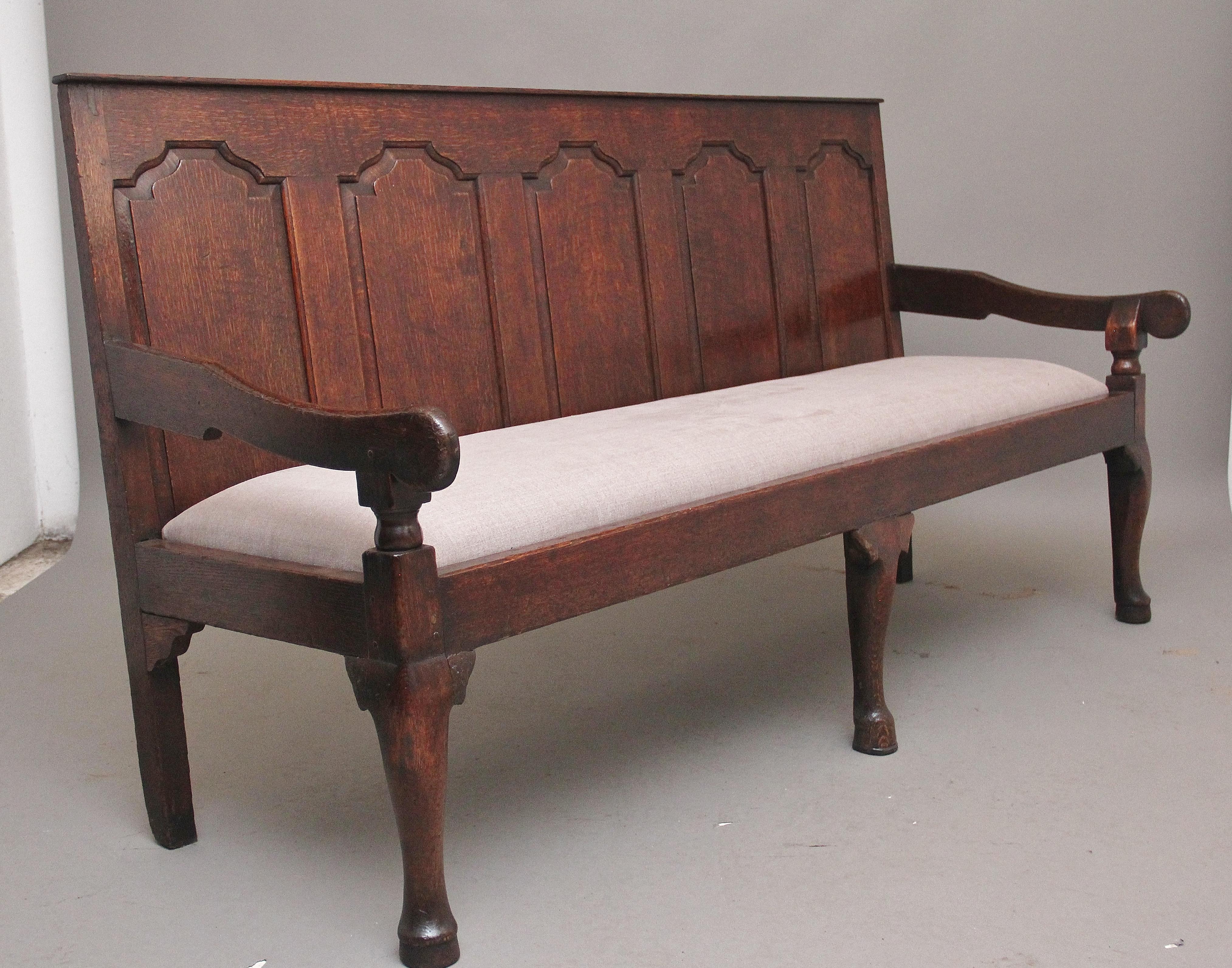 18th century Oak settle / bench the high back with five arched fielded oak panels flanked by down swept arms on turned supports enclosing the recently upholstered grey fabric seat, supported on cabriole front legs and square rear legs. circa 1780.