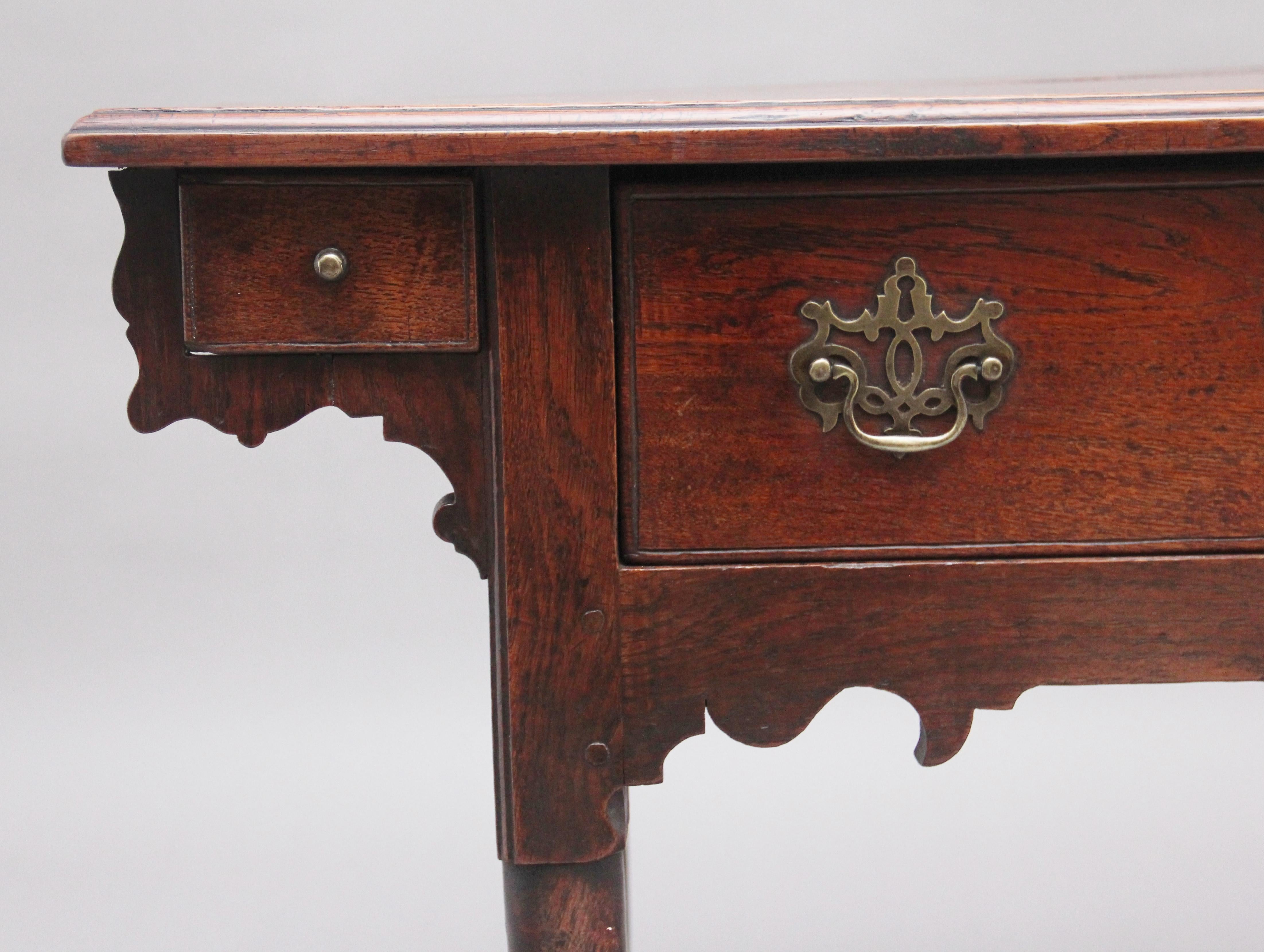 18th Century oak side table, the rectangular moulded edge top above an oak lined frieze drawer with the original brass fret handles and escutcheon, the table having two small drawers either end which are housed within decorative shaped corner