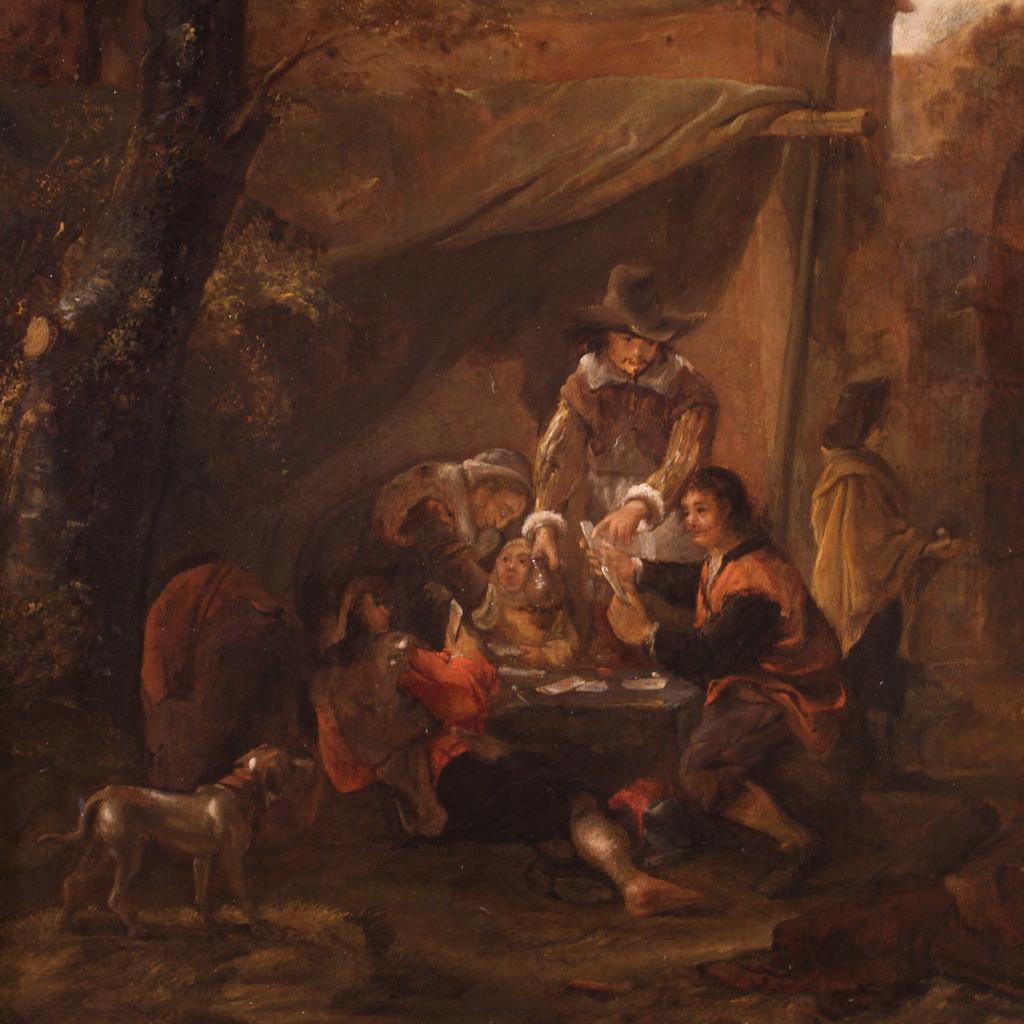 Escuela flamenca del siglo XVIII. Óleo sobre tabla que representa a jugadores de cartas sentados a una mesa al aire libre, probablemente junto a una posada. El posadero, representado de pie mientras ofrece una jarra de vino a los jugadores, parece