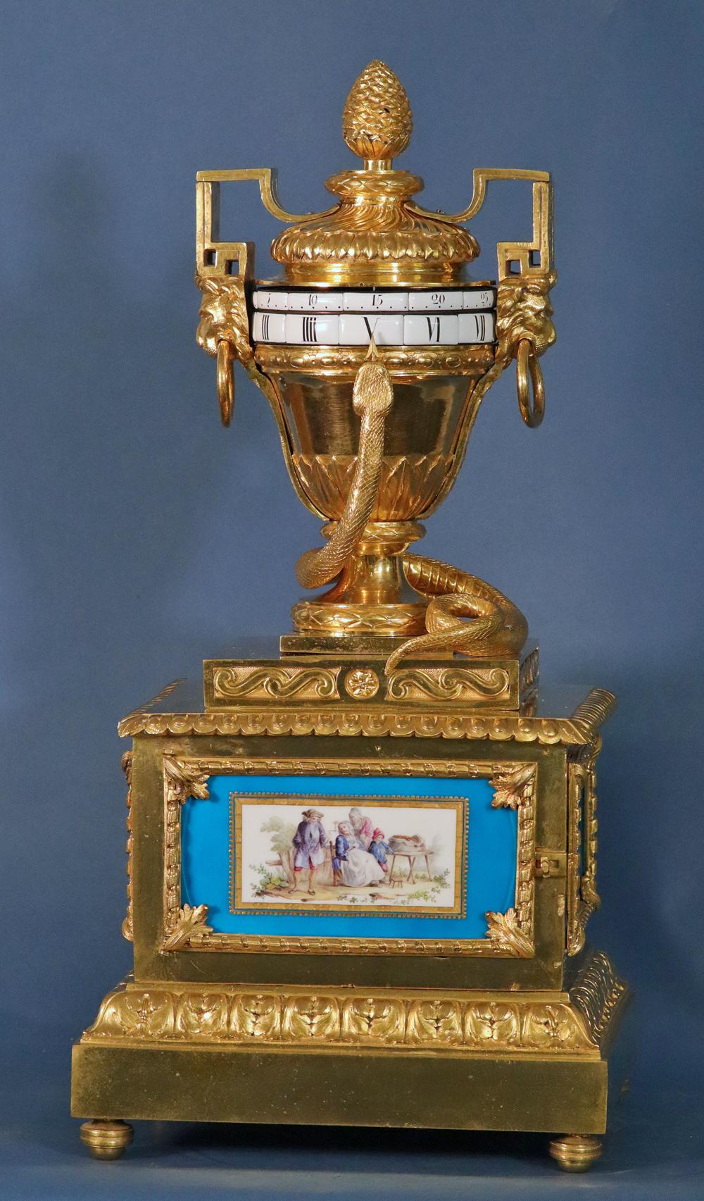 Louis XVI Ormolu Annular Clock with Sevres Panels. 
 
The ormolu case has a large urn flanked by lions with rings, a fluted top with a pinecone finial, a stepped case with burnished sides and a large well-cast ormolu snake that points to the time.