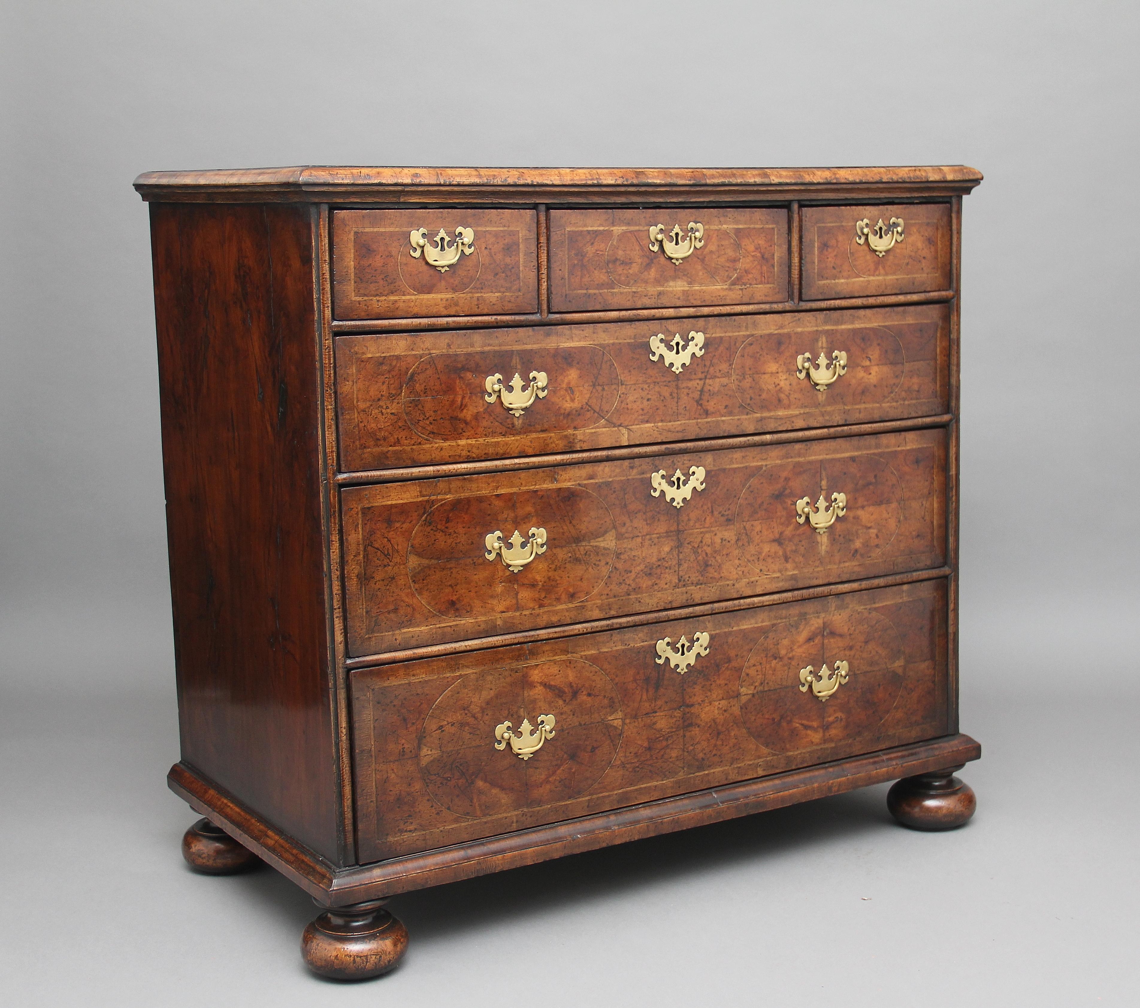 18th century and later re-vernered in yew wood oyster chest of drawers, having a cross grained thumb moulded edge top, with three short over three graduated long drawers with brass plate handles and escutcheons with D mouldings between the drawers,