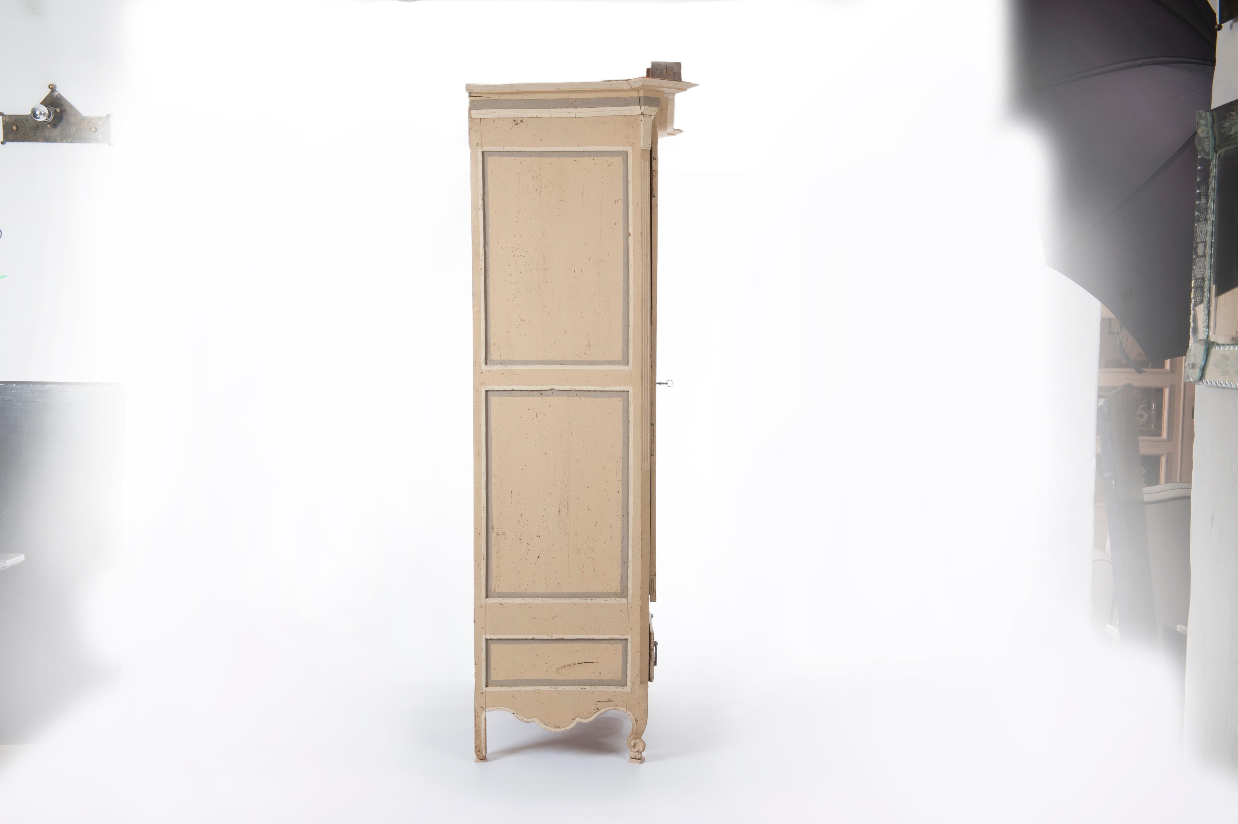 Armario francés del siglo XVIII de madera pintada al estilo rococó provenzal, con una puerta curvada y moldurada, un arcón, patas curvadas y cornisa. 
Pintado en un suave color amarillo, gris y hueso.
Extraordinario herraje de hierro, cerradura y