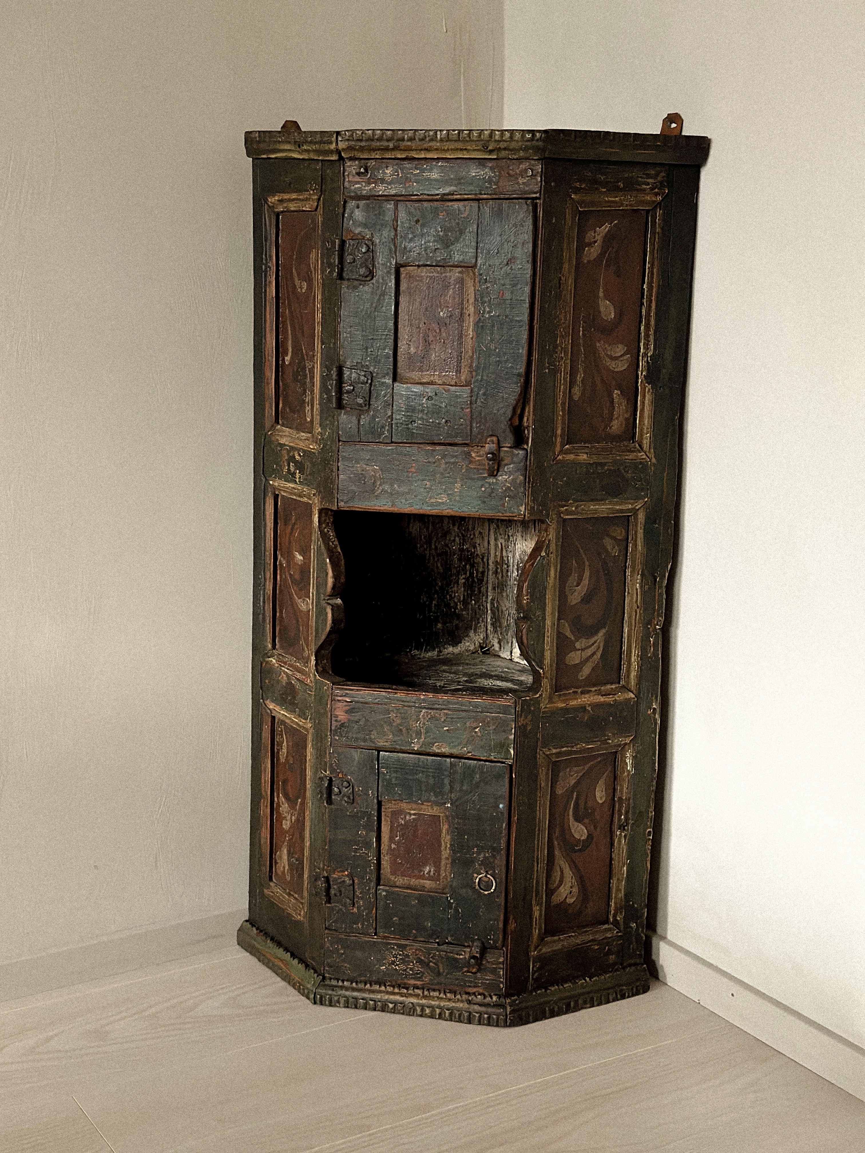 Eckschrank aus Trysil, Norwegen, um 1700. Handgefertigt aus Kiefernholz mit originell bemalten Oberflächen in tiefen Grün- und Rottönen, verziert mit traditionellen Blumenmotiven. Die abgenutzte Farbe und die geschnitzten Details zeugen von