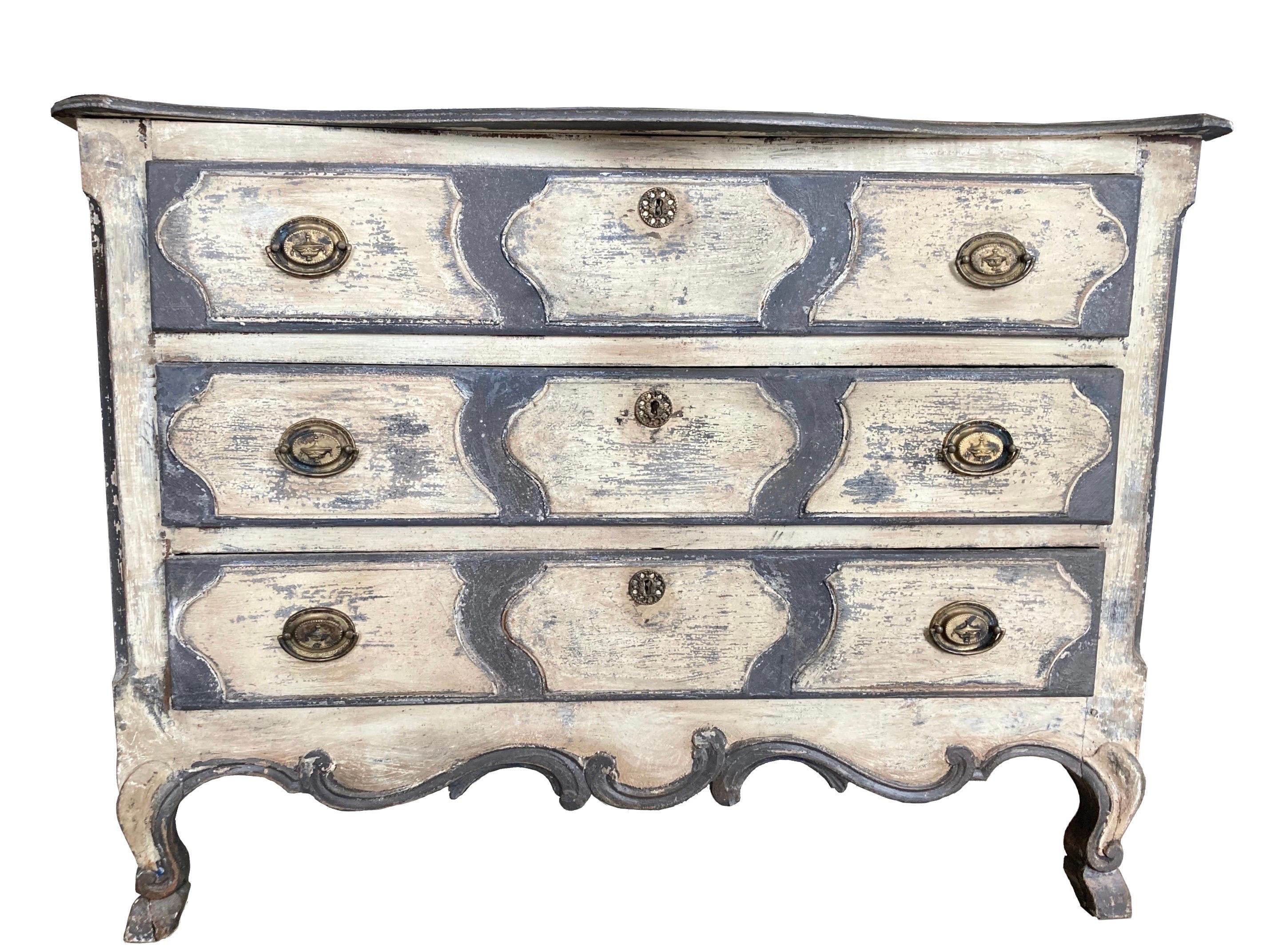 Louis XV commode made in France in the mid 1700s using oak and pegged construction. The chest features three overlay large drawers decorated on the front with raised, symmetrical hand carvings. The top is made of three boards with rounded edges and