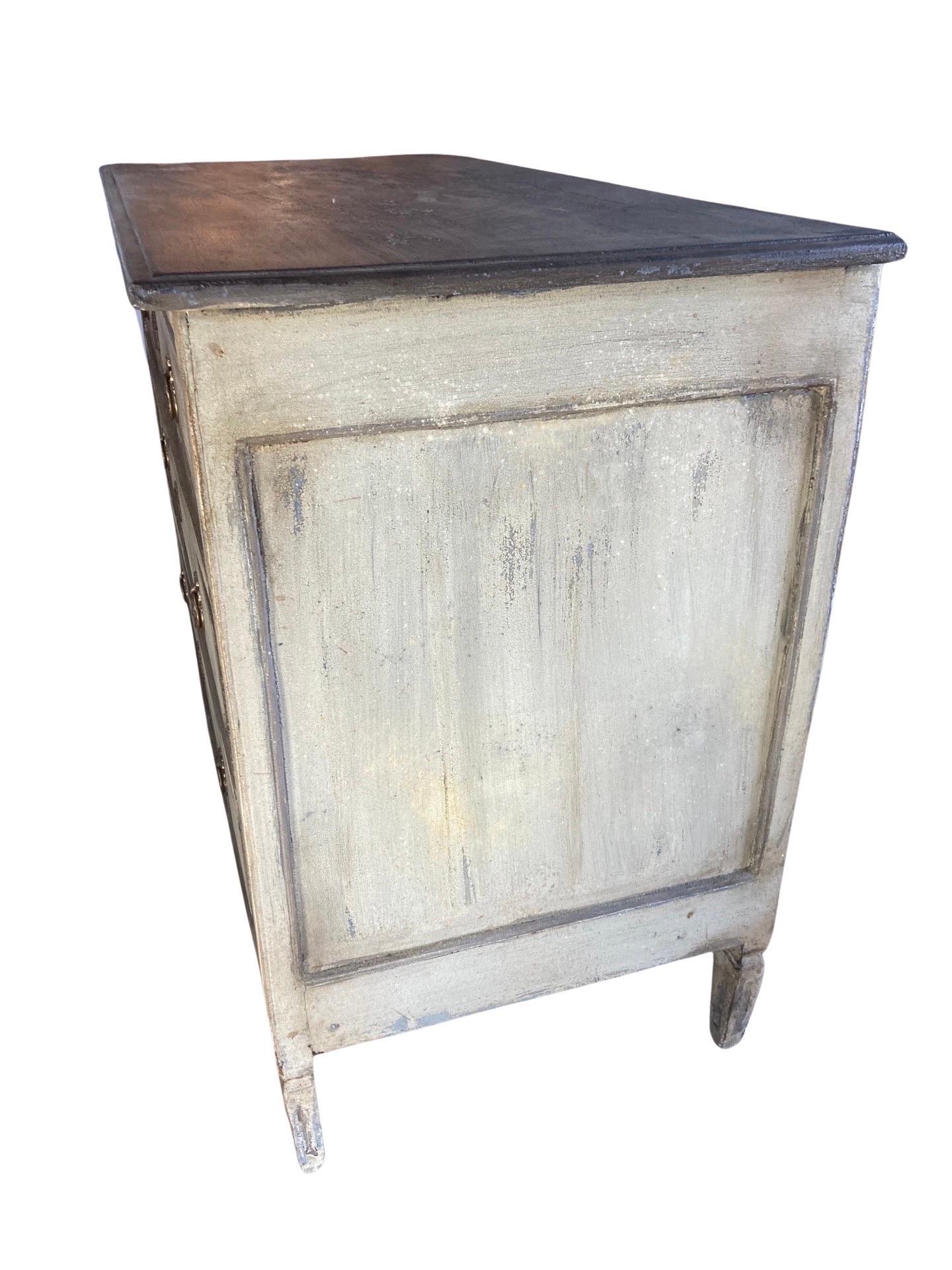 Painted Louis XVI commode hand-made in southern France in the mid 1700s using oak. The commode shows beautiful straight lines with some depth added by hand-carved fluting and two-toned paint. The commode features three inset drawers made of