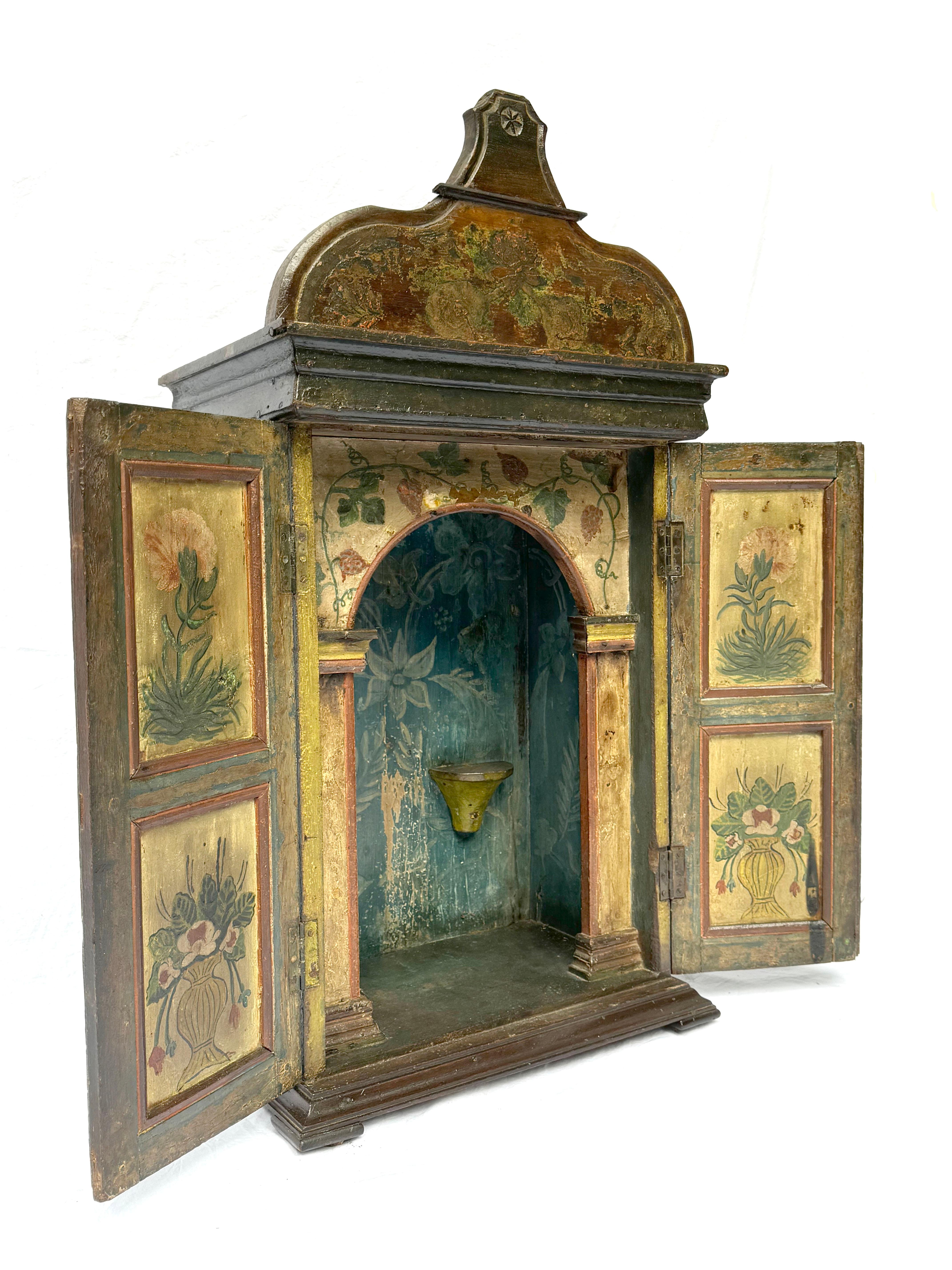 Este exquisito santuario colonial sudamericano del siglo XVIII es un notable ejemplo del arte devocional de la época, que muestra la fusión de la influencia europea y la artesanía local característica de la época barroca en la América Latina