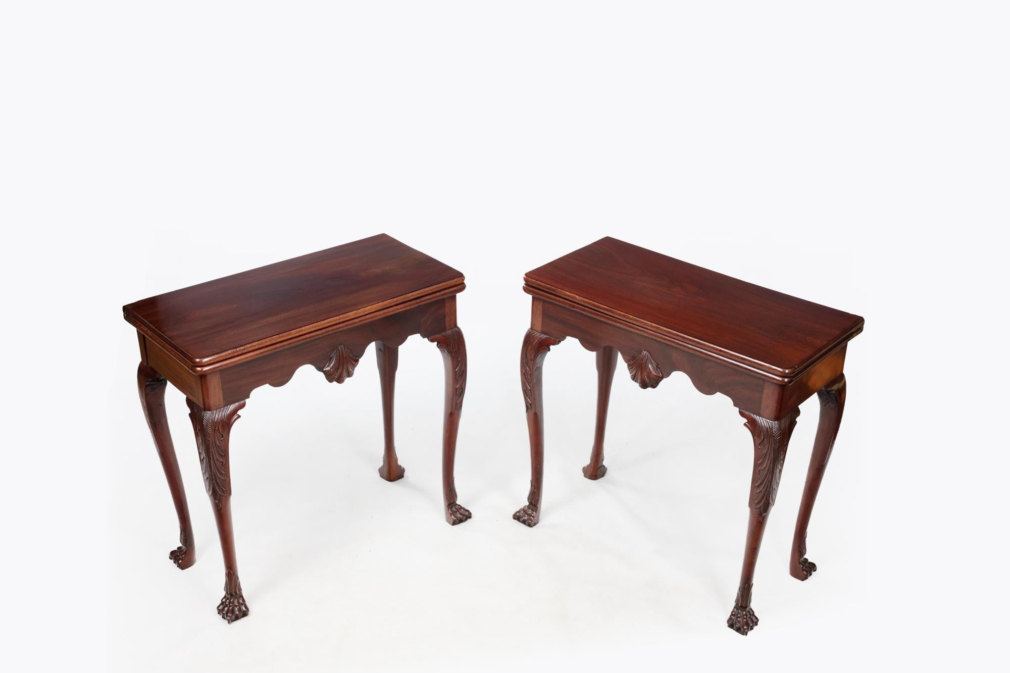 18th Century pair Irish mahogany fold-over card tables with green baize interiors. The pair with central carved scallop shell detail are flanked on either side by cabriole legs with trailing acanthus leaf carvings, terminating in hairy paw