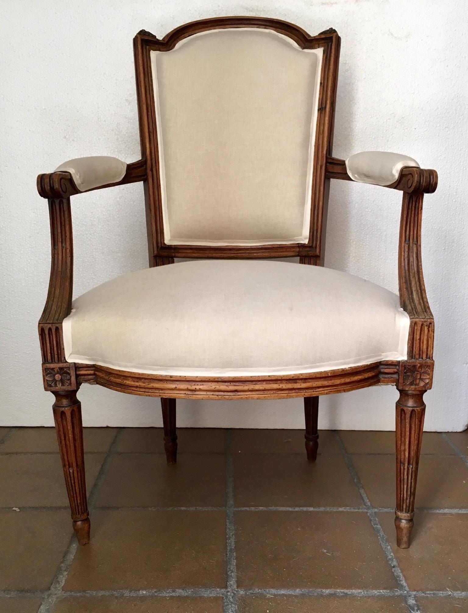 Pair of armchairs or fauteuils, Luis XVI, late 18th century, in walnut wood with back sculpted in guilloche, on fluted tapering legs, the interior has been reinforced and restored, upholstery.
