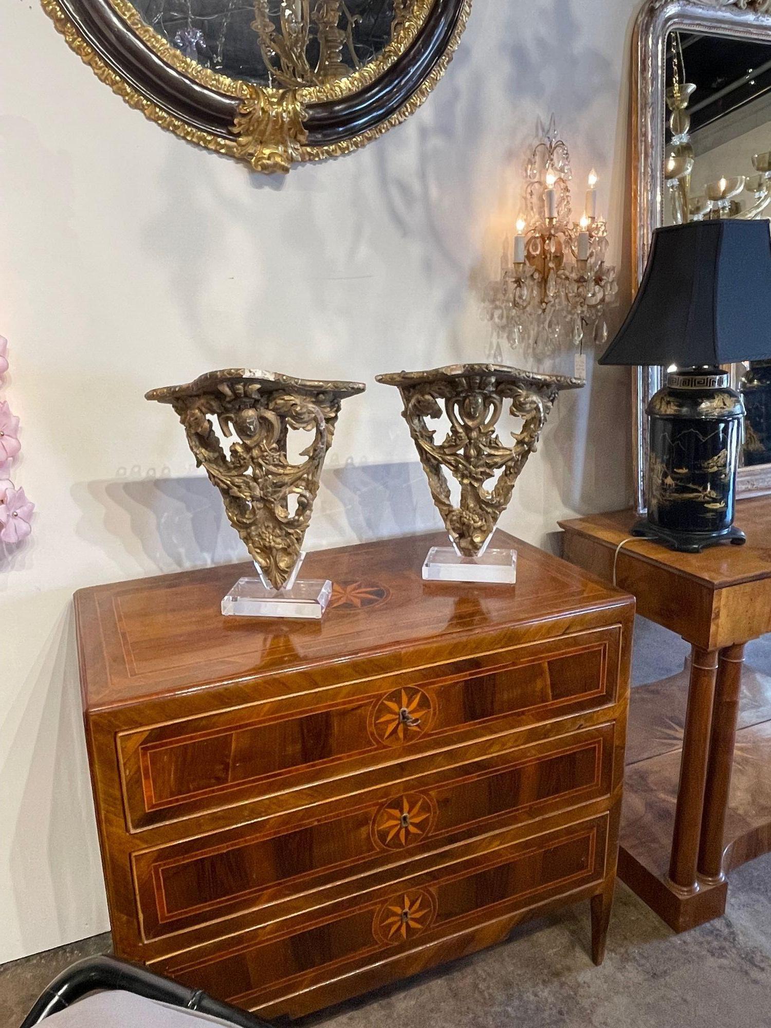 Decorative pair of 18th century Italian carved and giltwood corner brackets on mounted lucite stands. Fabulous accessories that make a real impact!