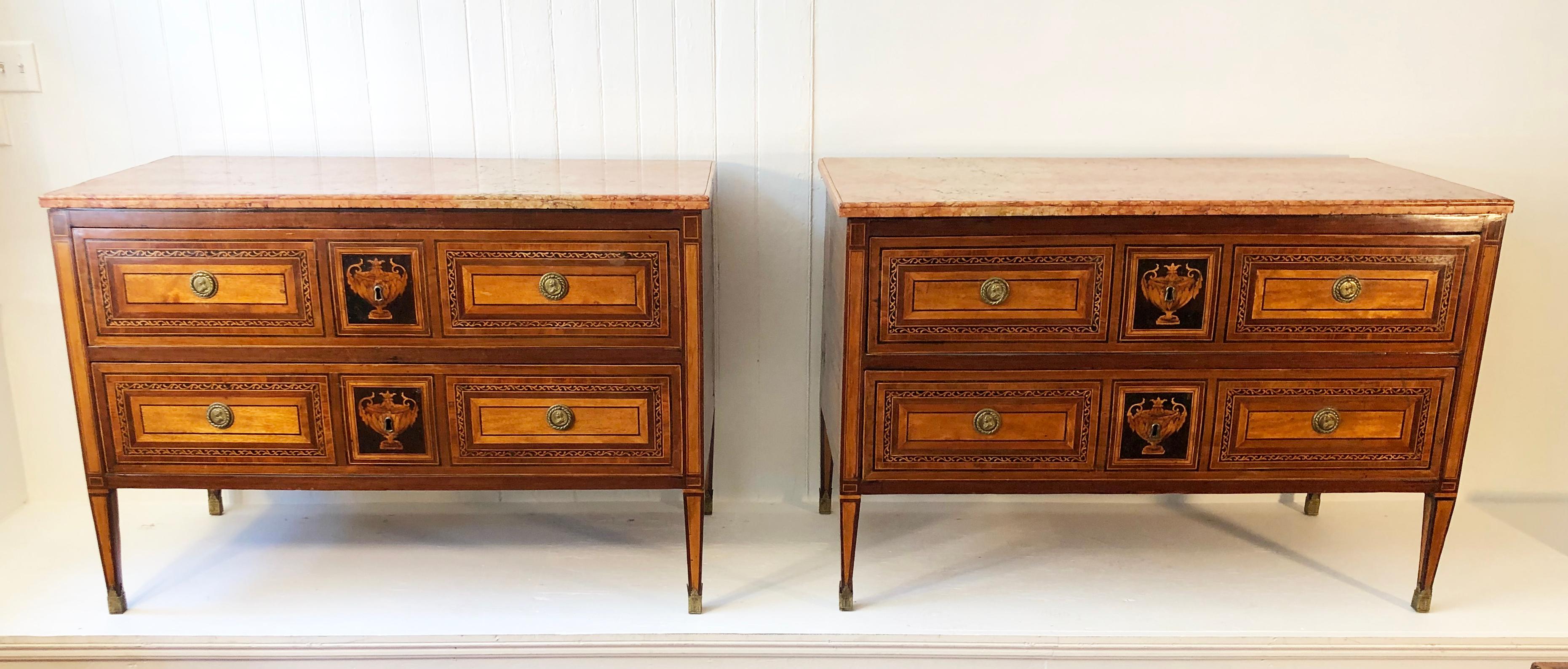 Pair of marble top two drawer commodes with mahogany, ebony, satinwood and walnut inlay. This Pair of commodes are in the manner of Giuseppe Maggiolini. The commodes are elegantly inlaid. The classic design with the drawers having a center inlaid
