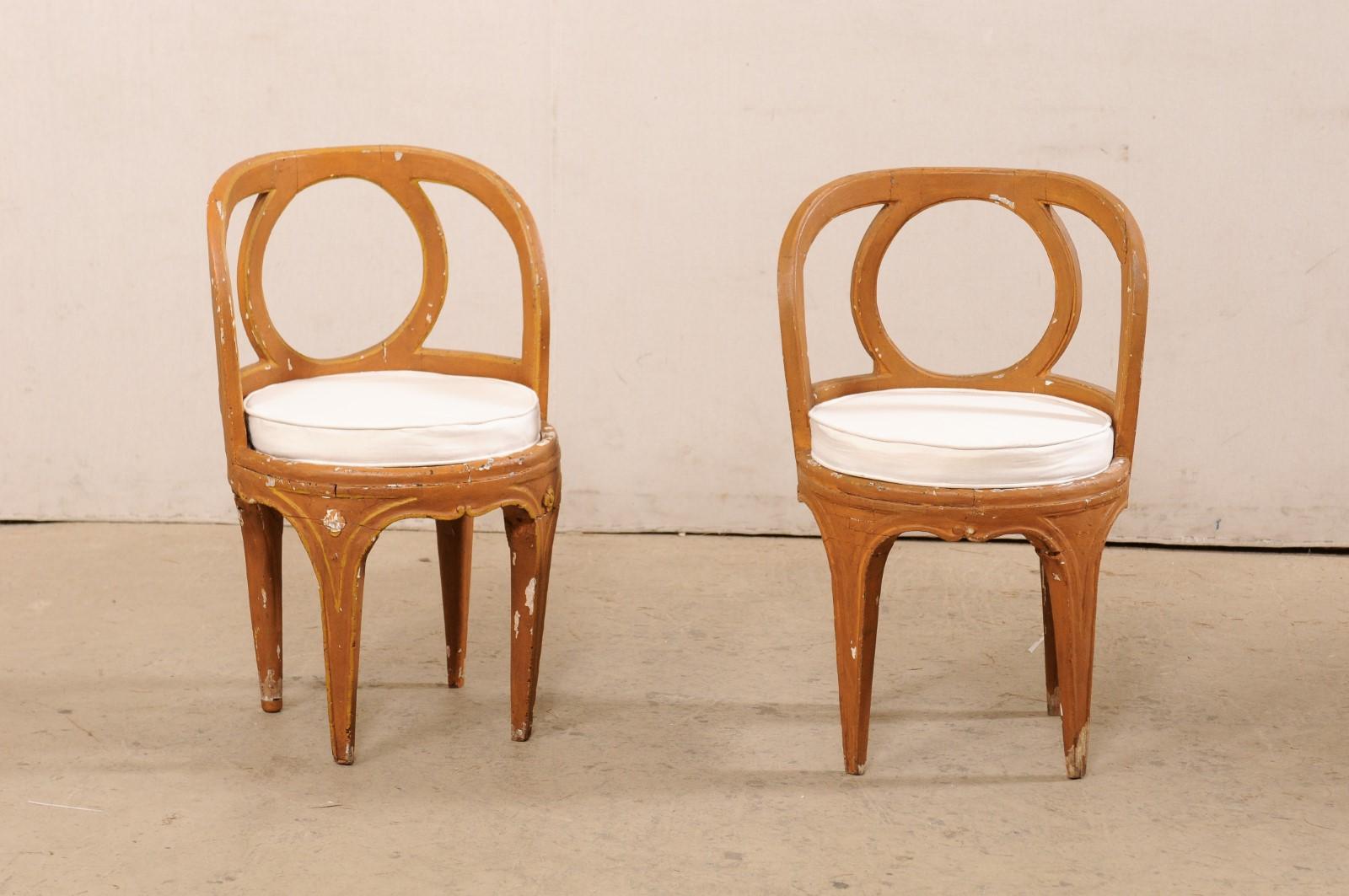 A Venetian pair of rounded and carved-wood accent chairs from the 18th century. This antique pair of Venetian chairs from Italy each have round-shaped seats with rounded back set with circular back-splat at center, and raised on four tapering legs