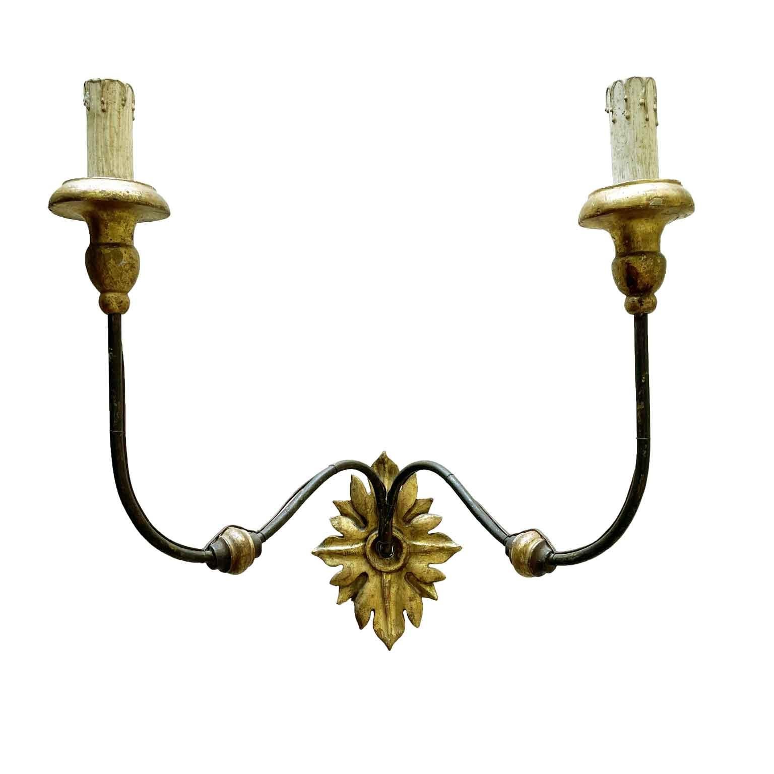 Pair of Renaissance style mid-18th century two-arm Italian sconces,  curved hand-forged arms  decorated with wooden elements and ending with turned giltwood bobeches. Feature a lovely giltwood back panel with shaped foliate carving.
Tuscan origin,