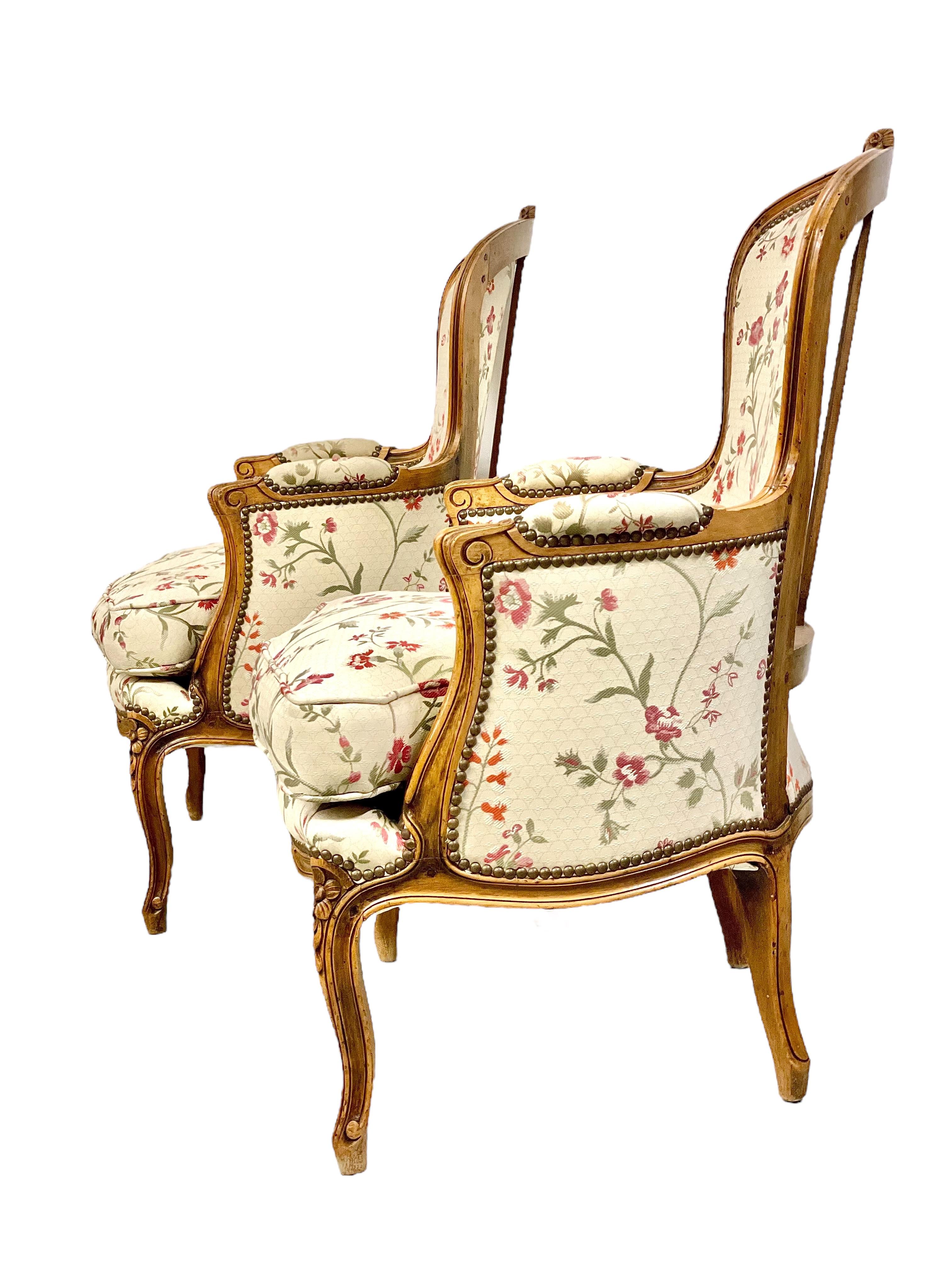 Superbe paire de fauteuils bergère de style Louis XV du XVIIIe siècle, fabuleusement tapissés d'un luxueux tissu floral couleur crème et reposant sur d'élégants pieds cabriole. Ces chaises sont magnifiquement fabriquées à la main en hêtre et