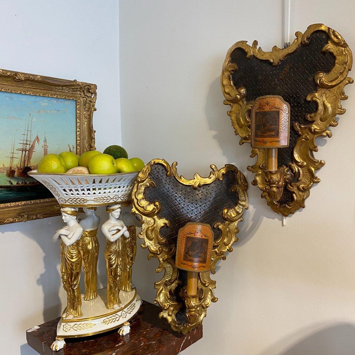 We present you this splendid pair of rare single-light, Louis XV Rocaille-style gilded wood wall sconces from the 18th century. They originate from Italy and are imbued with the essence of the Baroque era. The central part of these sconces has a