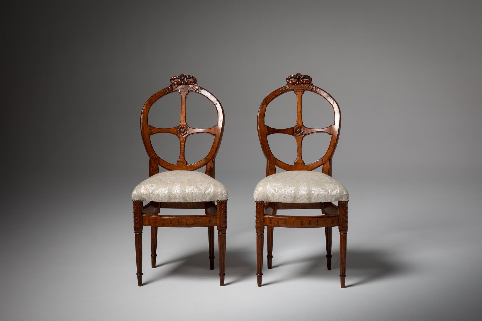 Paire d'élégantes chaises d'Europe du Nord de la fin du XVIIIe siècle, présentant une exécution exquise et des éléments décoratifs raffinés. Ces chaises présentent des motifs de rubans sculptés de manière complexe sur les cadres en bois, une