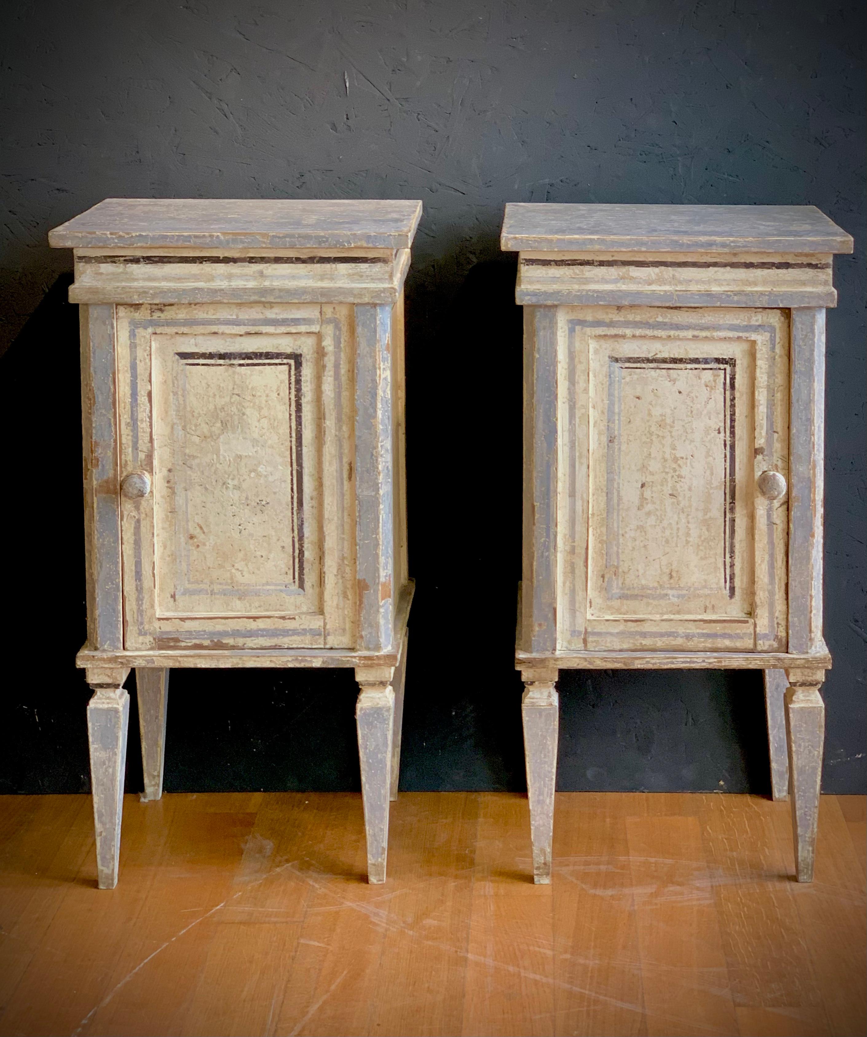 Elegant pair of nightstands in fir wood painted in lean tempera on a chalky background. Classic pastel colors in shades of gray, with a single door, supported by four truncated pyramidal legs. Typical TUSCAN manufacture from the neoclassical period.