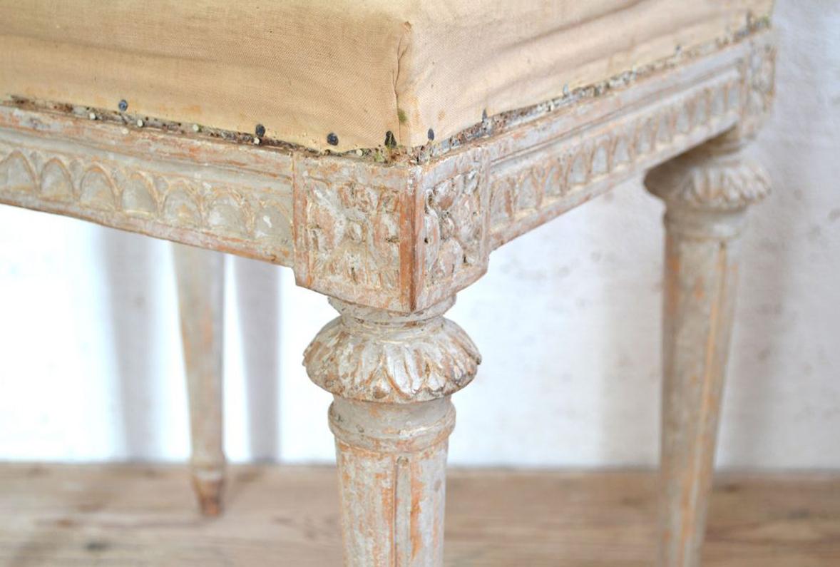 A rare pair of Swedish stools from the Gustavian period with round caps adorned with acanthus leaves. These charming benches have been hand-scraped to reveal the original paint. There is carved egg and dart detail on the seat frame and carved