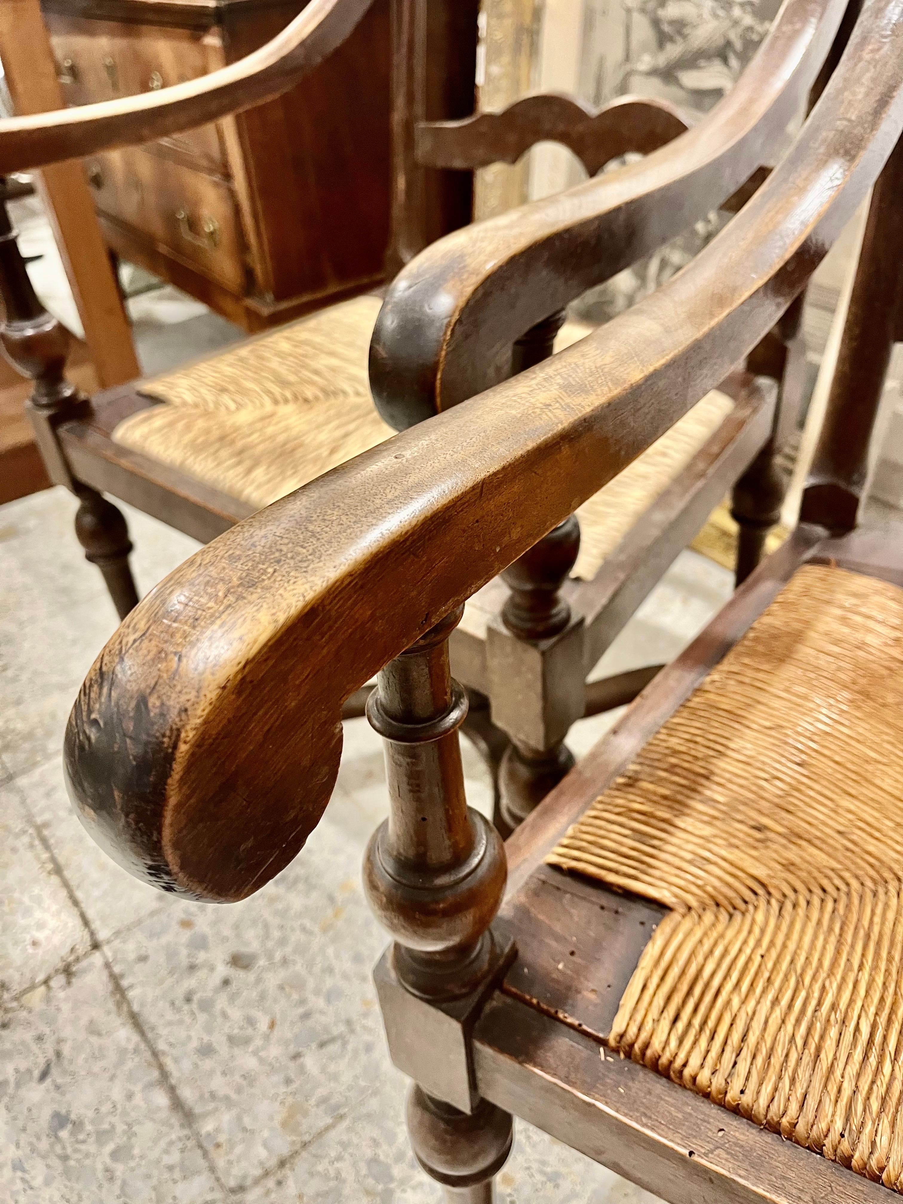 Coppia di poltrone provenzali in legno di faggio, schienale con quattro barre intagliate, gambe tornite e traversa a forma di X, la seduta è in paglia, una di esse è originale, l'altra è stata incorporata nuova tramite restauro.
