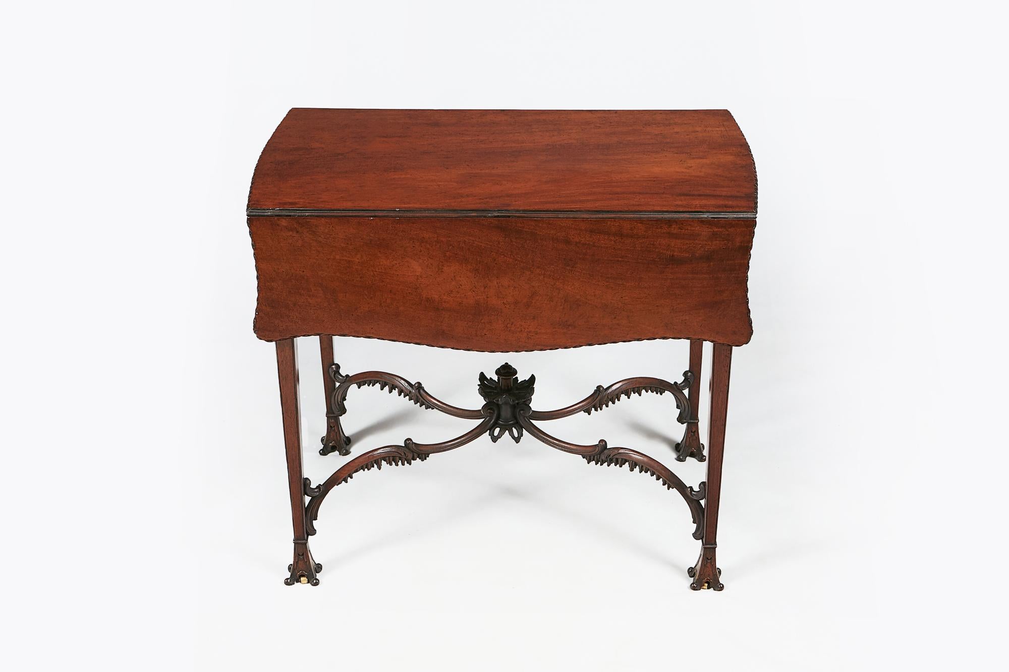 18th century mahogany pembroke table in the style of Chippendale, the shaped butterfly top with fret moulded edges raised over single drawer with brass pulls, carved bellflower and foliate motif over shaped frieze supported on slender tapering leg