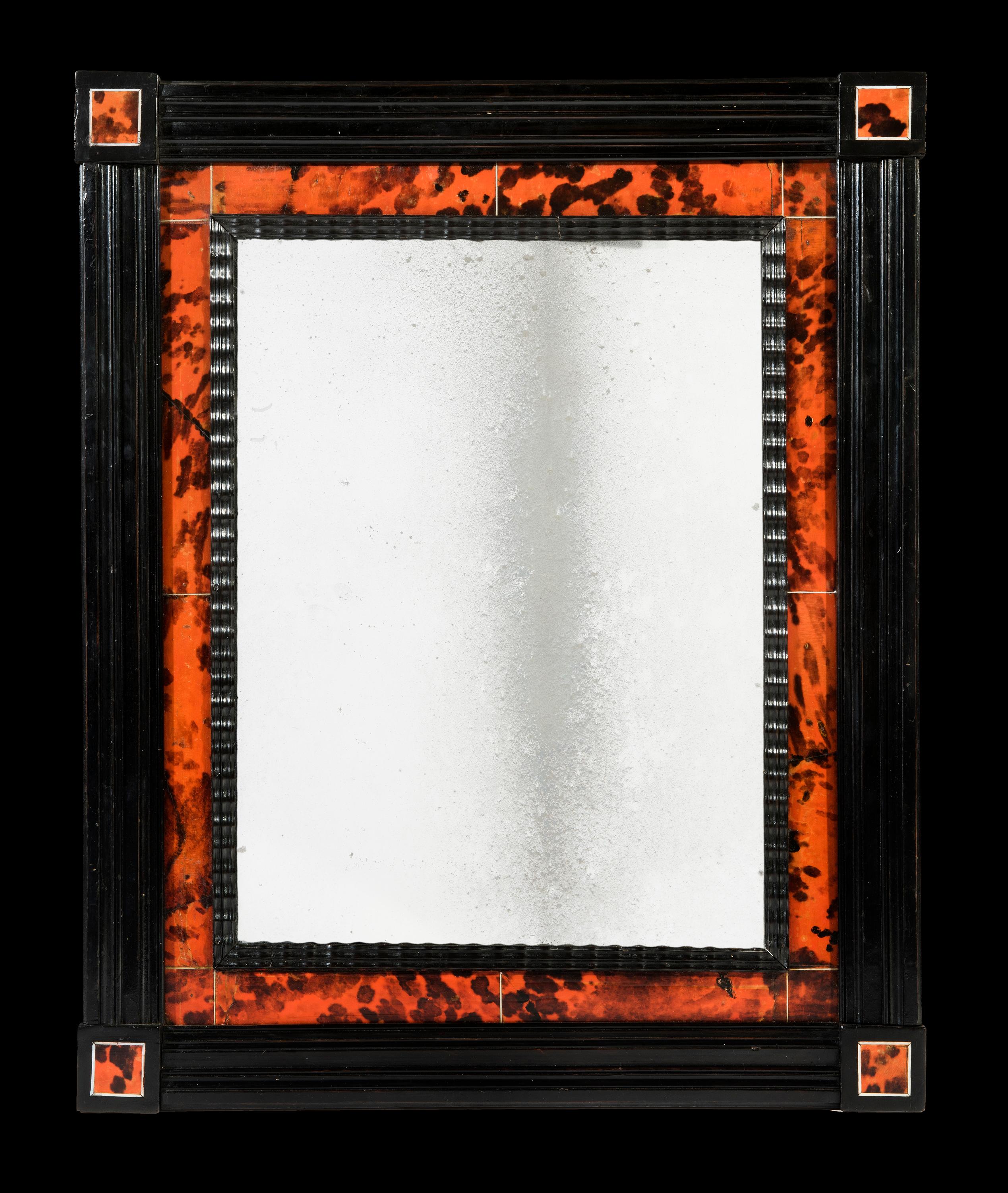 The rectangular reeded ebonised frame is decorated on all four concerns with stained red tortoise shell panels and ivory borders. The red tortoise shell sleeve is veneered in vertical sections and divided by corner squares and ivory borders. The