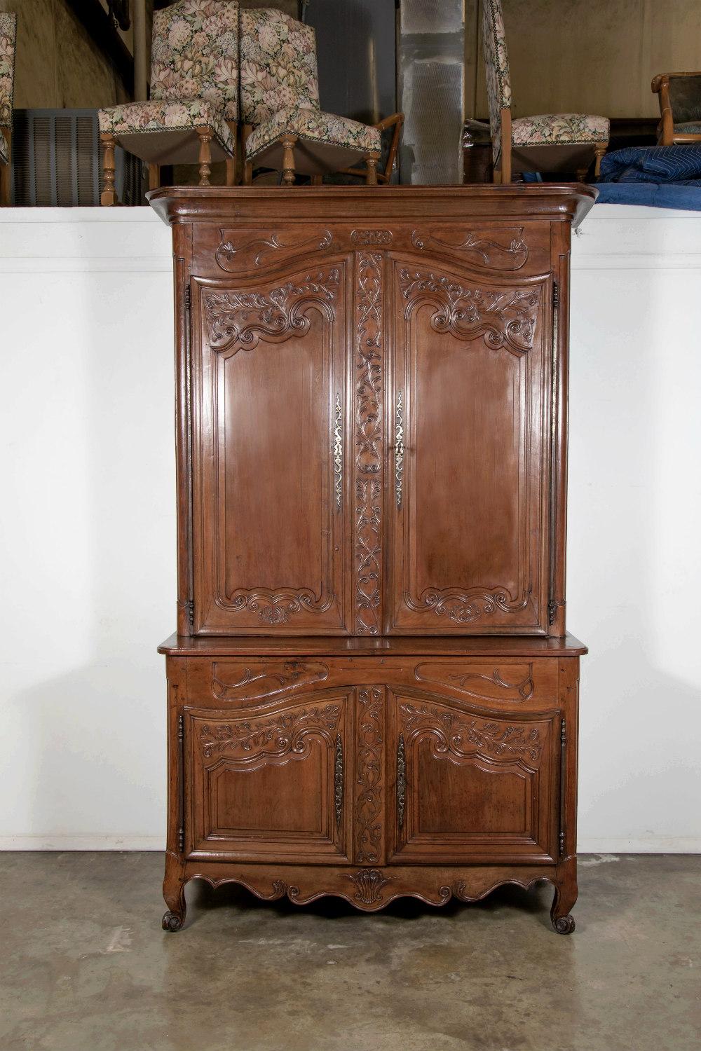 Monumental 18th century country French Louis XV buffet deux corps handcrafted by talented artisans in the Loire Valley. Expertly crafted and sculpted in select French walnut, this period chateau piece features an upper cabinet having a carved frieze