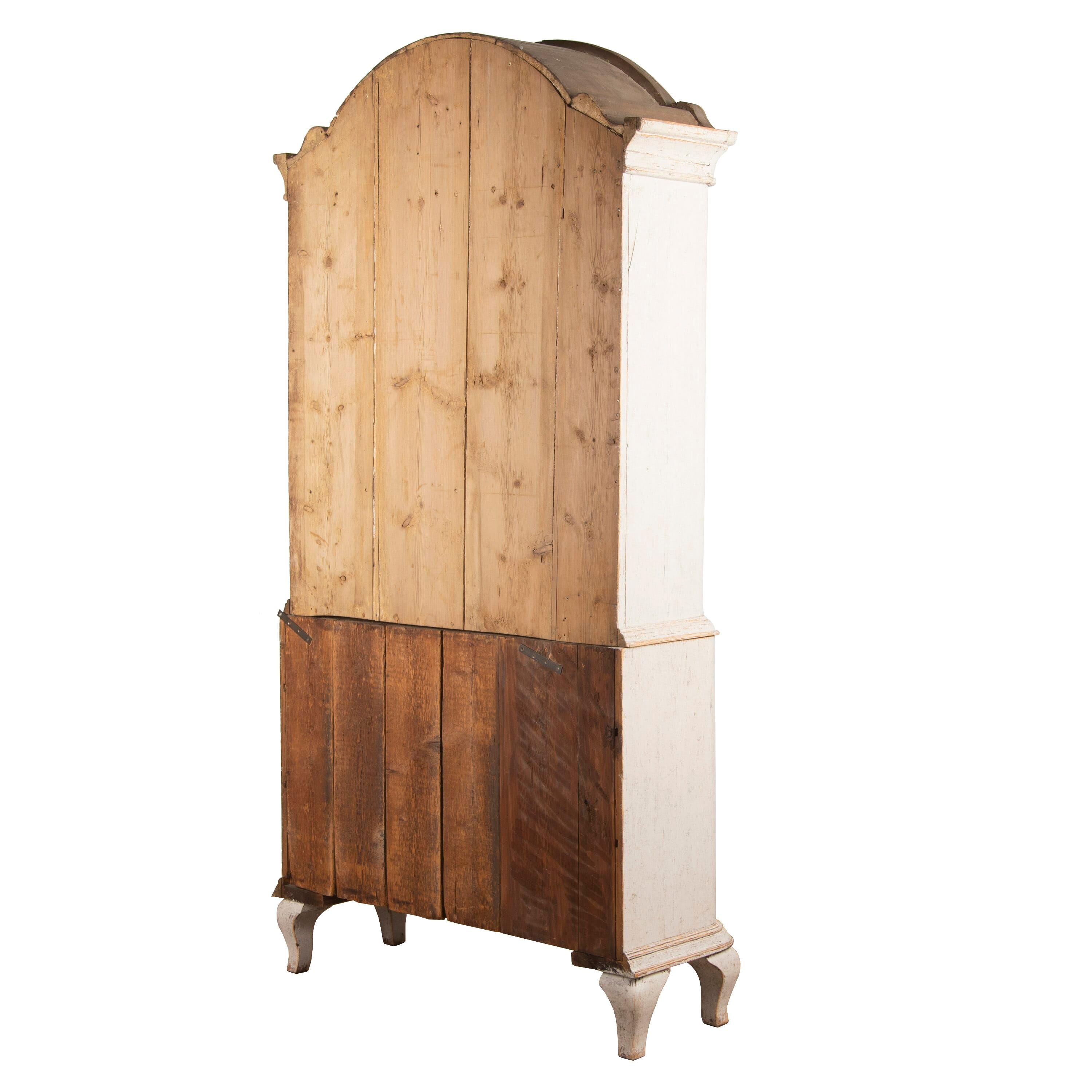 A period Rococo cabinet from the area of Jamtland, Sweden with a deep arch carved pediment. Two doors with decorative beading to the doors open to useful storage, below there are two short and two further long drawers. This piece has been repainted