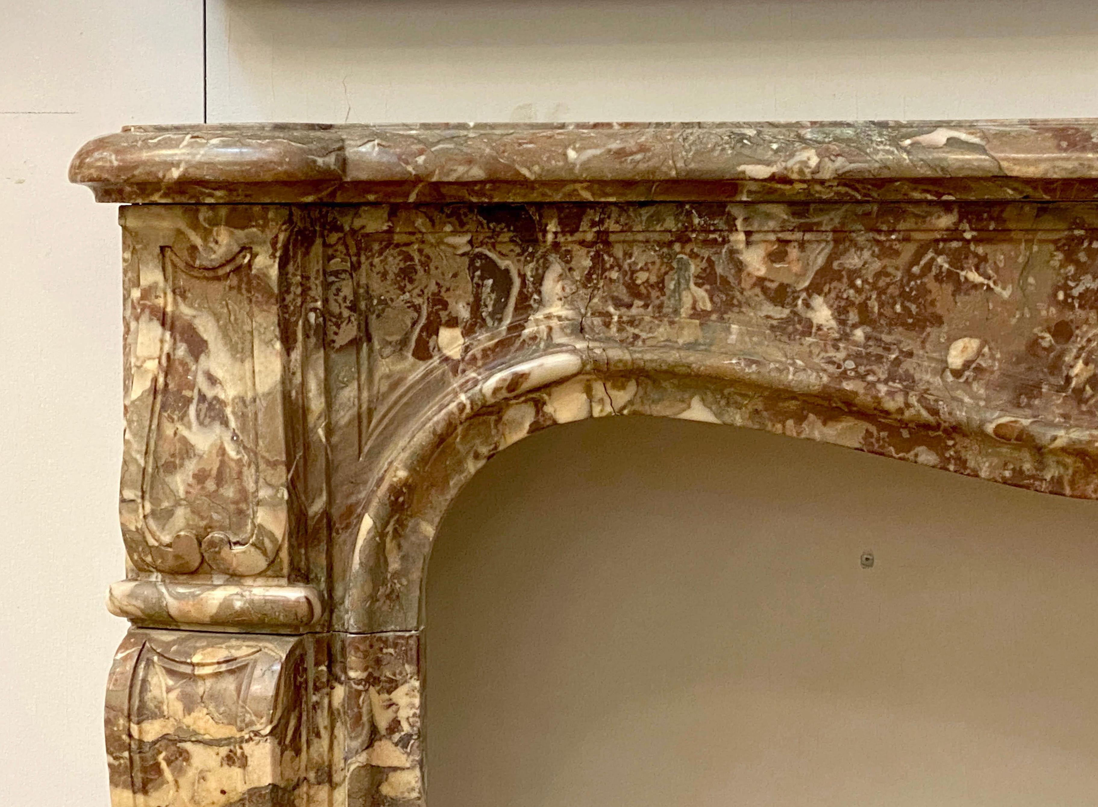 Petite antique 18th century French marble mantel in the Louis XV featuring light toned veins of brown, white, and gray. Hand carved Acanthus leaf motif is at the center of the mantel cross piece. Reclaimed from 936 5th Avenue in NYC. This can be