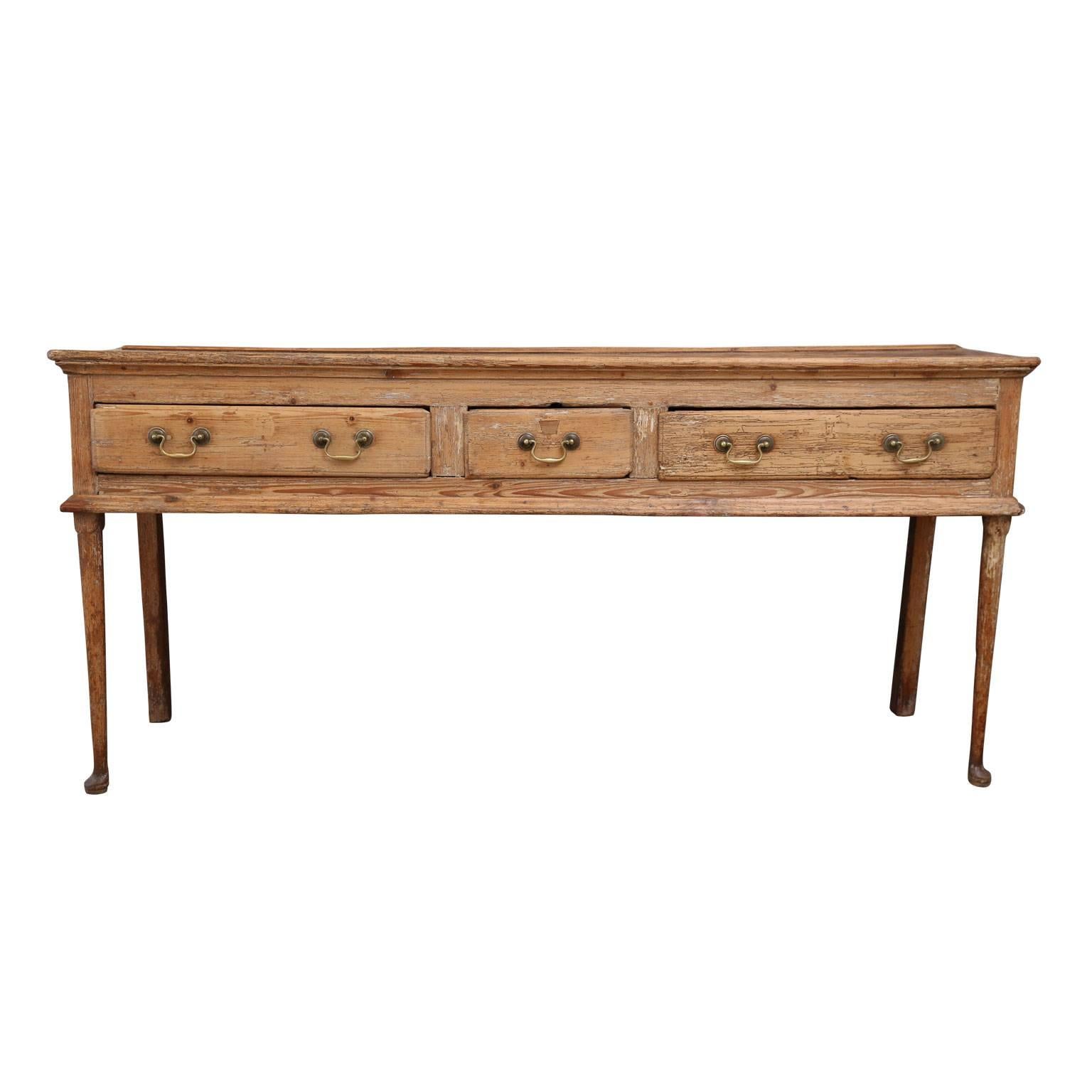 18th century pine dresser with three deep drawers and slender front legs with pad feet. Dated to circa 1775, this English antique is in excellent condition with panelled sides, top trimmed in simple elegant molding and period swan neck brass pulls