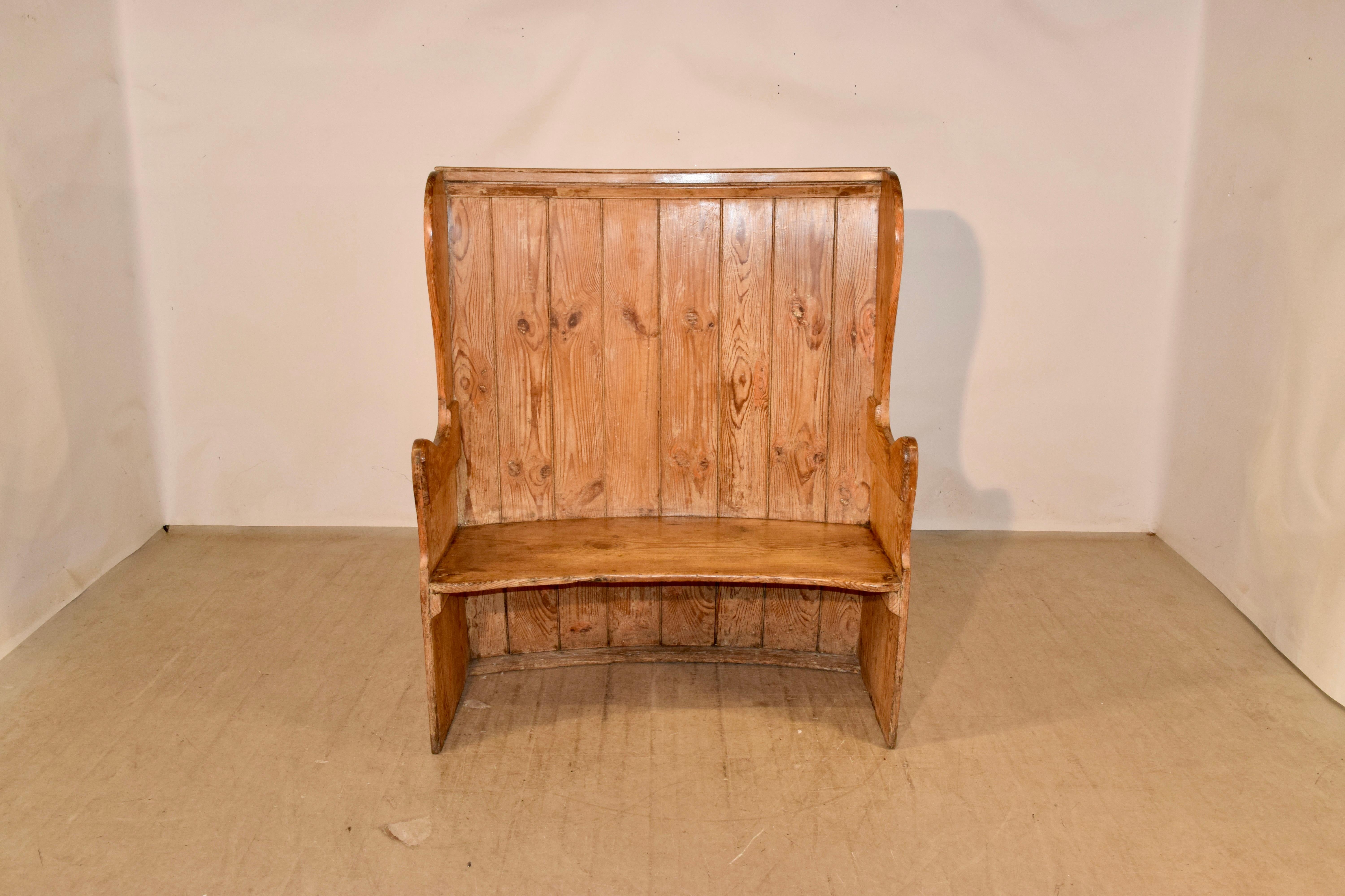 Wonderful 18th century English pine settle with a gently curved form. It has a plank back with wing sides and gently curved arms, surrounding a single plank seat.