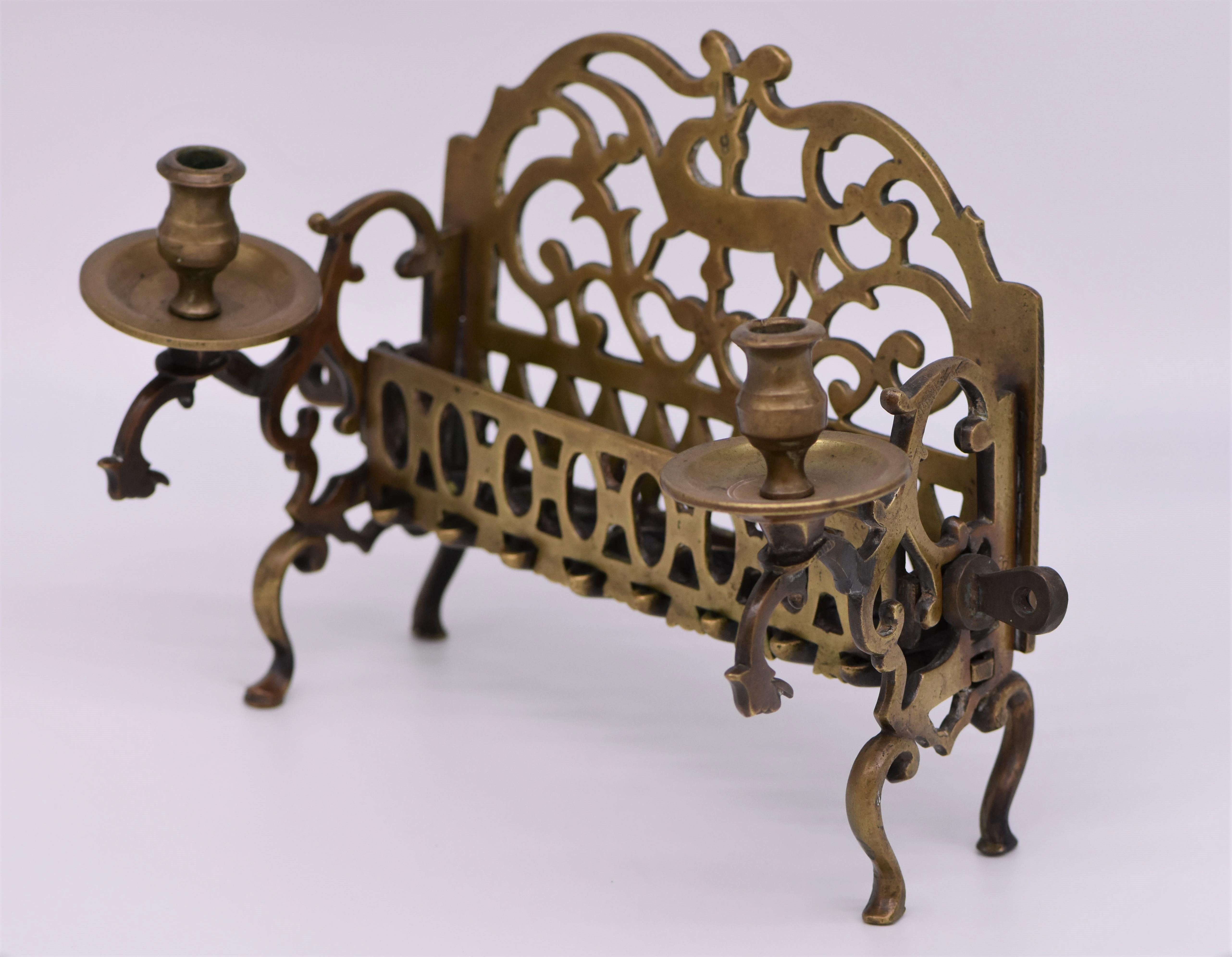 The backplate is cast and featuring a deer in the center surrounded by open scrollwork. The side panels fitted with two servant lights, fronted by a row of eight oil fonts. Scholars theorize that these Polish Chanukah lamps that bear two servant