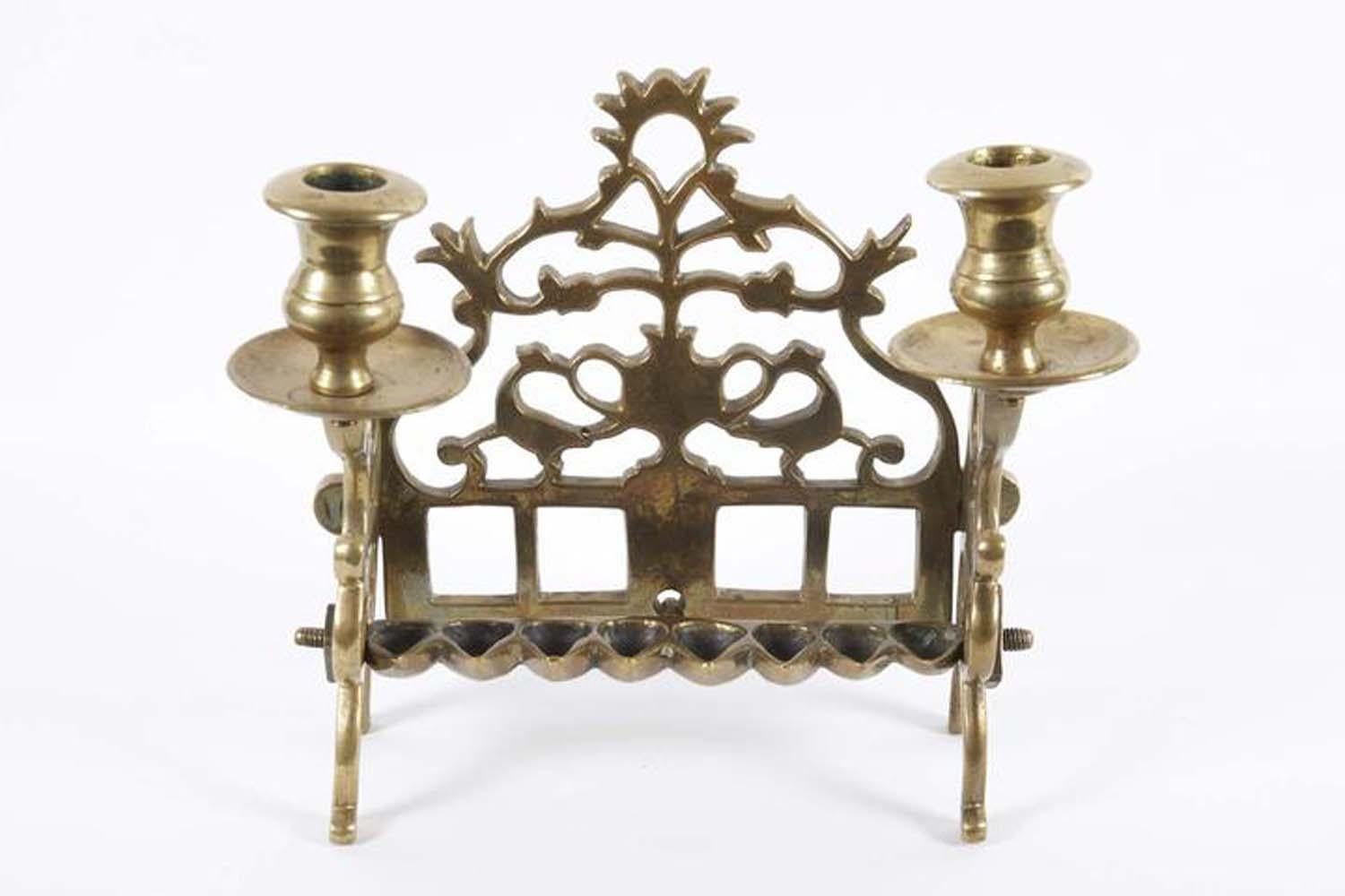 The backplate is cast and pierced with a central two-handled vase of flowers, flanked by fully formed birds with their heads turned outward. The side panels fitted with two servant lights, fronted by a row of eight oil fonts. Scholars theorize that