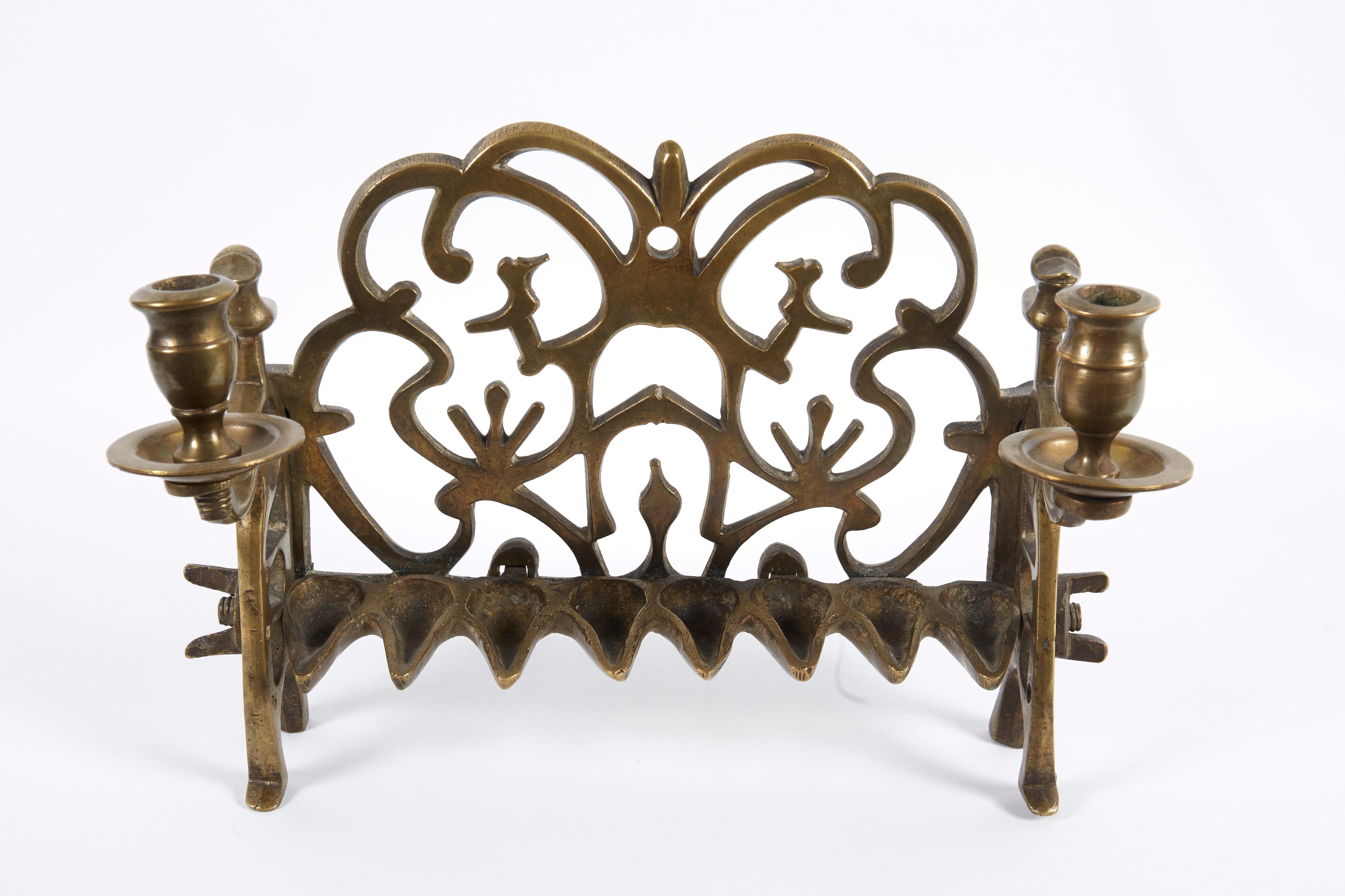 The backplate is cast and featuring two birds in the center surrounded by open scrollwork. The side panels fitted with two servant lights, fronted by a row of eight oil fonts. Scholars theorize that these Polish Chanukah lamps that bear two servant