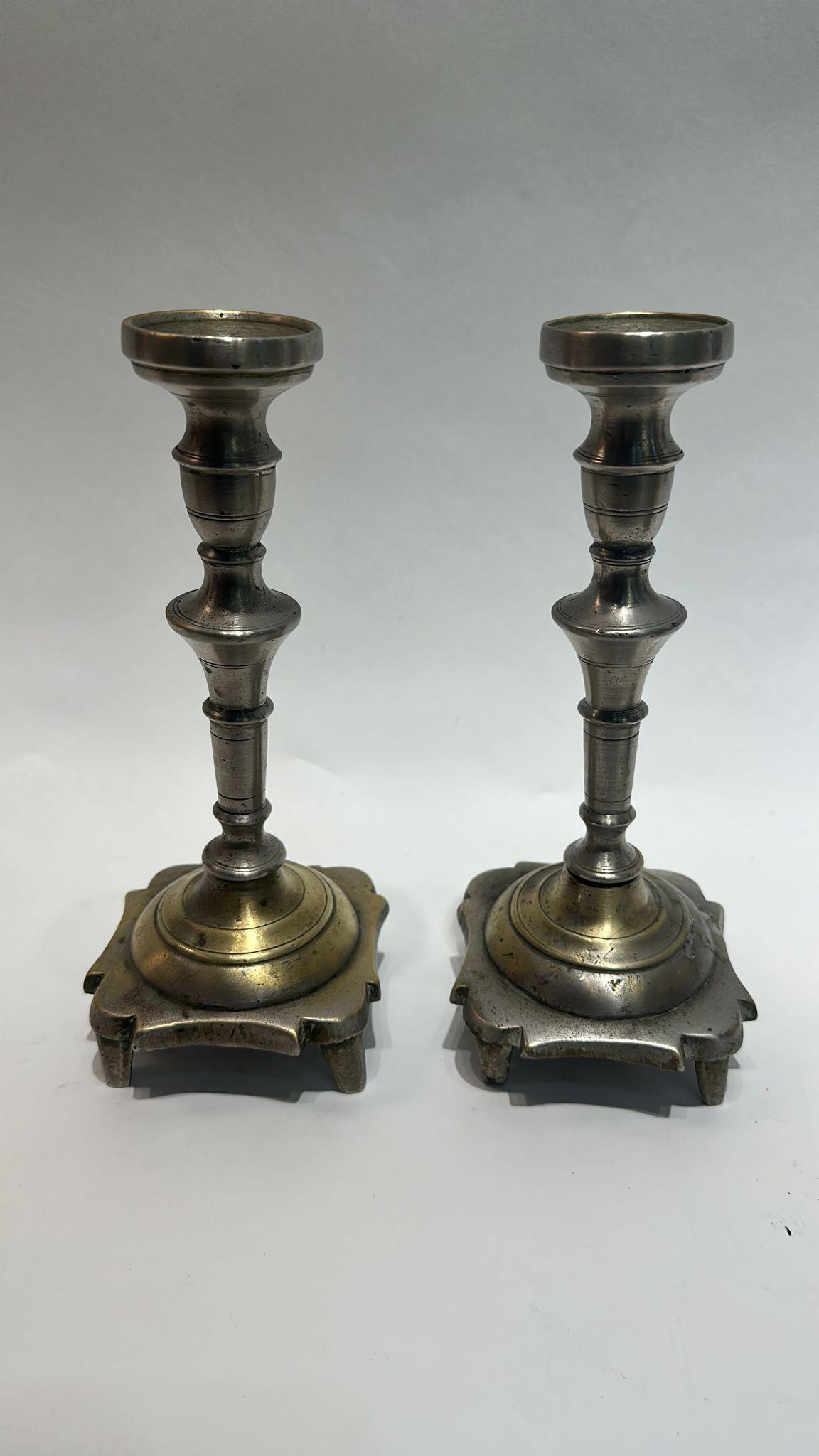 Cette paire rare et authentique de bougeoirs polonais du XVIIIe siècle incarne l'artisanat rustique mais profondément symbolique des shtetls juifs d'Europe de l'Est. Fabriquées en laiton avec des traces d'argenture d'origine, ces pièces présentent
