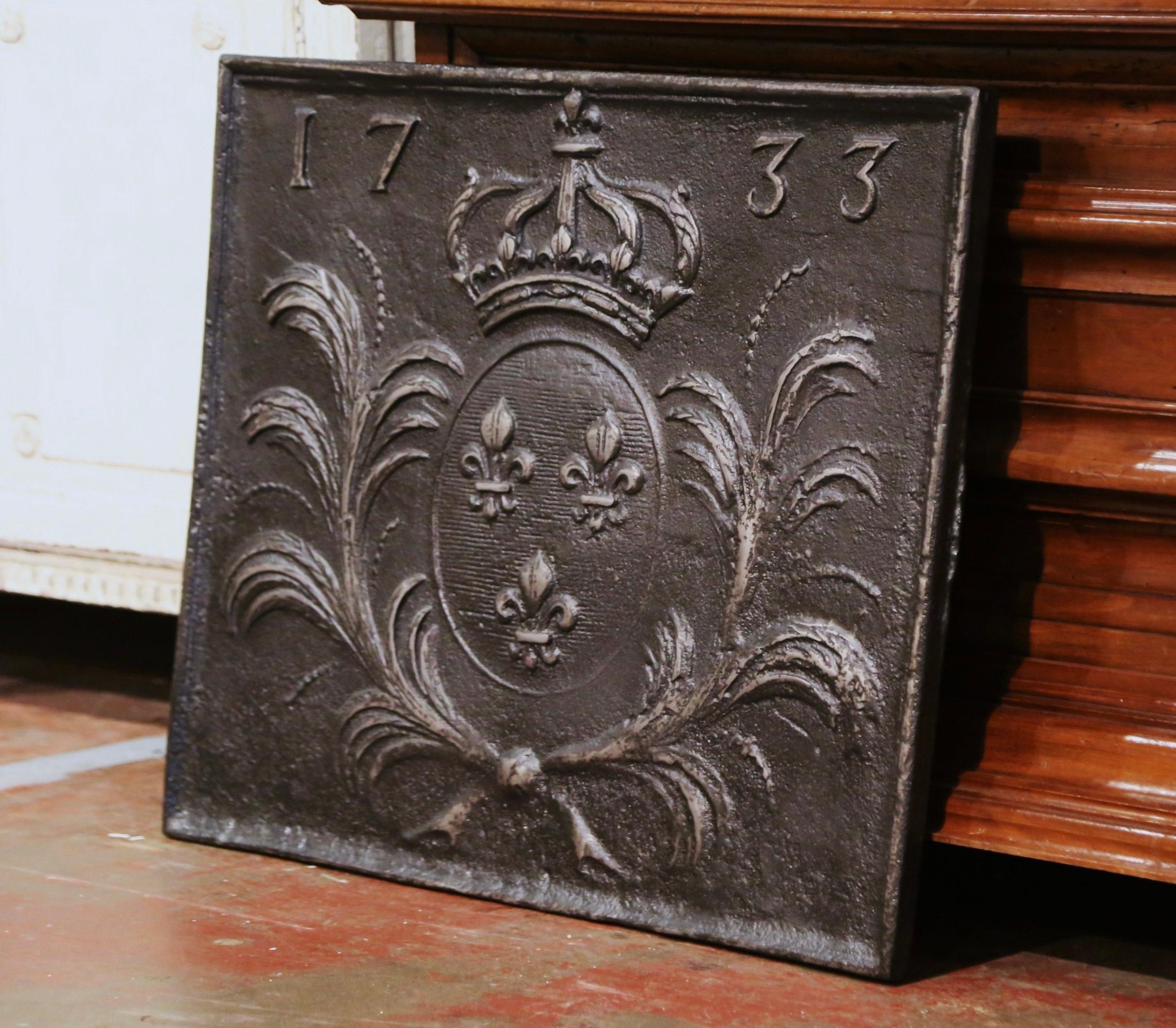 Decorate your fireplace with this elegant antique fire back. Crafted circa 1770 and almost square in shape, the French ornate fireplace essential with a date of 1733 at the pediment, features a crest of the kingdom of Louis XIV with three