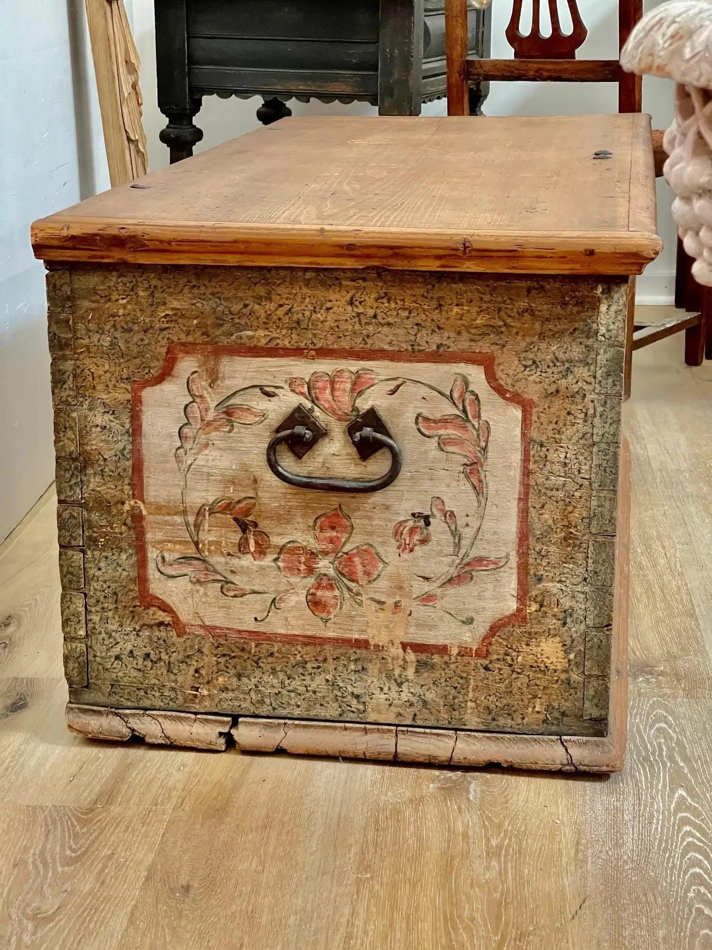 Polychrome floral painted blanket chest, Pennsylvania , featuring hinged rectangular lid fitted with original wrought-iron strap hinges, interior with lidded till, each end with wrought-iron bail handle. Retains likely original paint-decorated