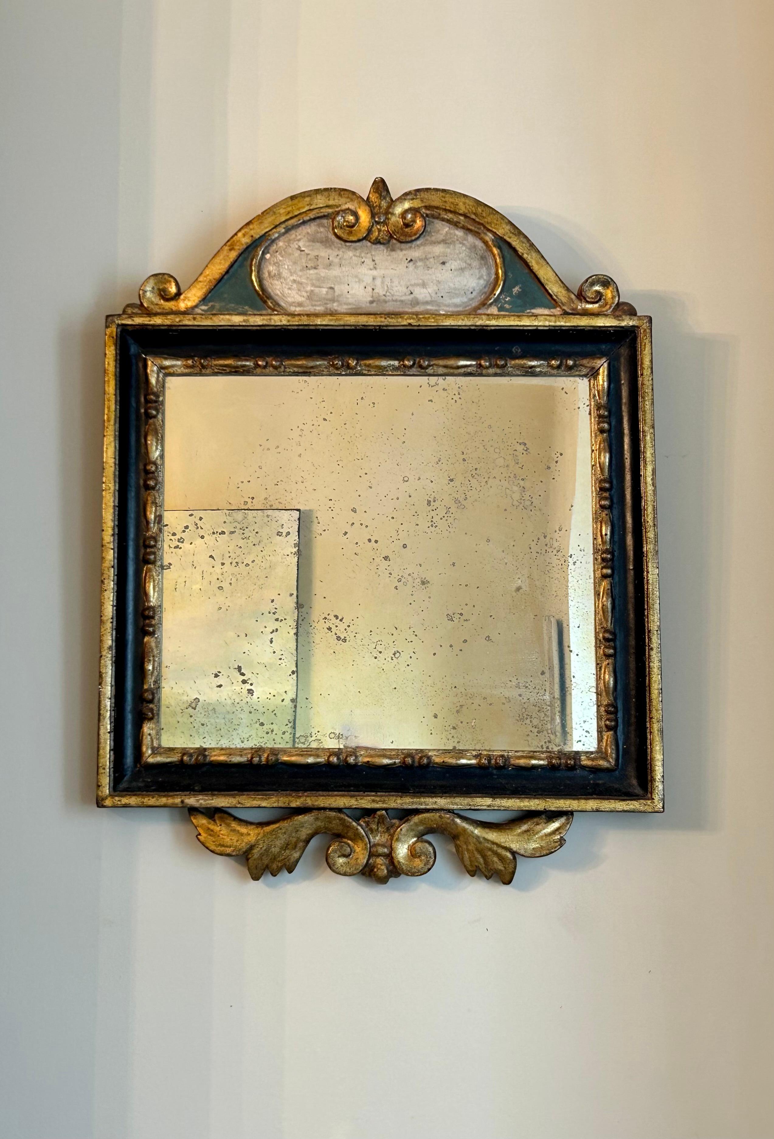 Il s'agit d'un magnifique miroir du XVIIIe siècle avec sa vitre d'origine, probablement de France ou d'Italie.  Peint en noir et vert avec de belles dorures sur le cadre et les volutes supérieures et inférieures, avec un cartouche peint en blanc sur