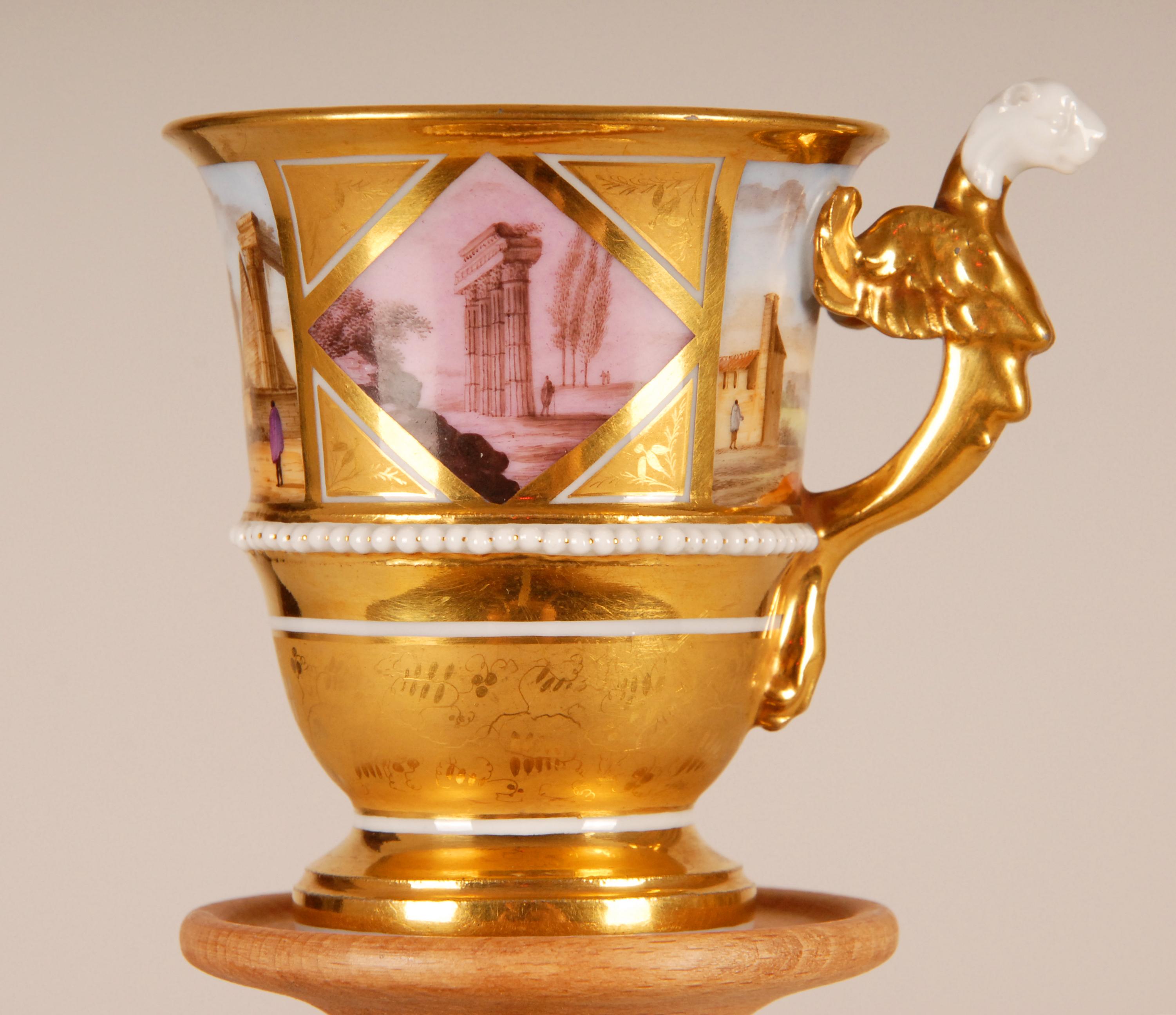 Antique French Locre & Russinger Taza y platillo de porcelana dorada francesa con asa figurada
En la copa cuatro paisajes en reserva (2 rombos) y una hilera de perlas en relieve. En las esquinas de las reservas, interior y parte inferior frutas y