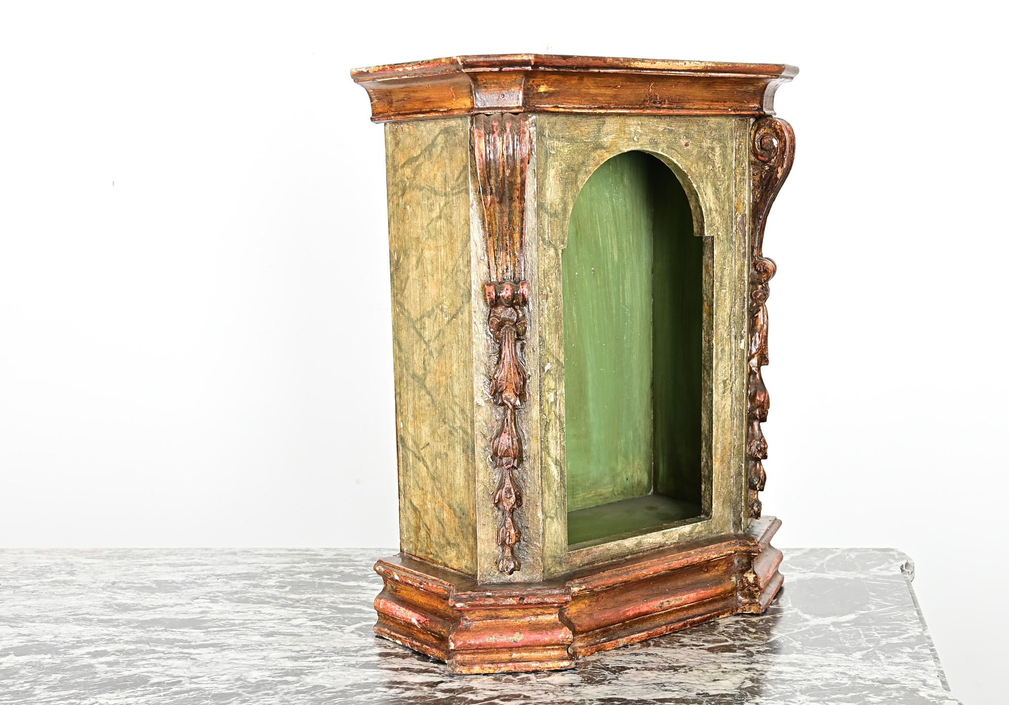 A fantastic oratory or tabletop altar from 18th century Portugal, made of carved, painted, and gilded wood taking the form of a small cabinet (where religious statuary would be displayed). The niche interior is painted a leafy shade of green, framed