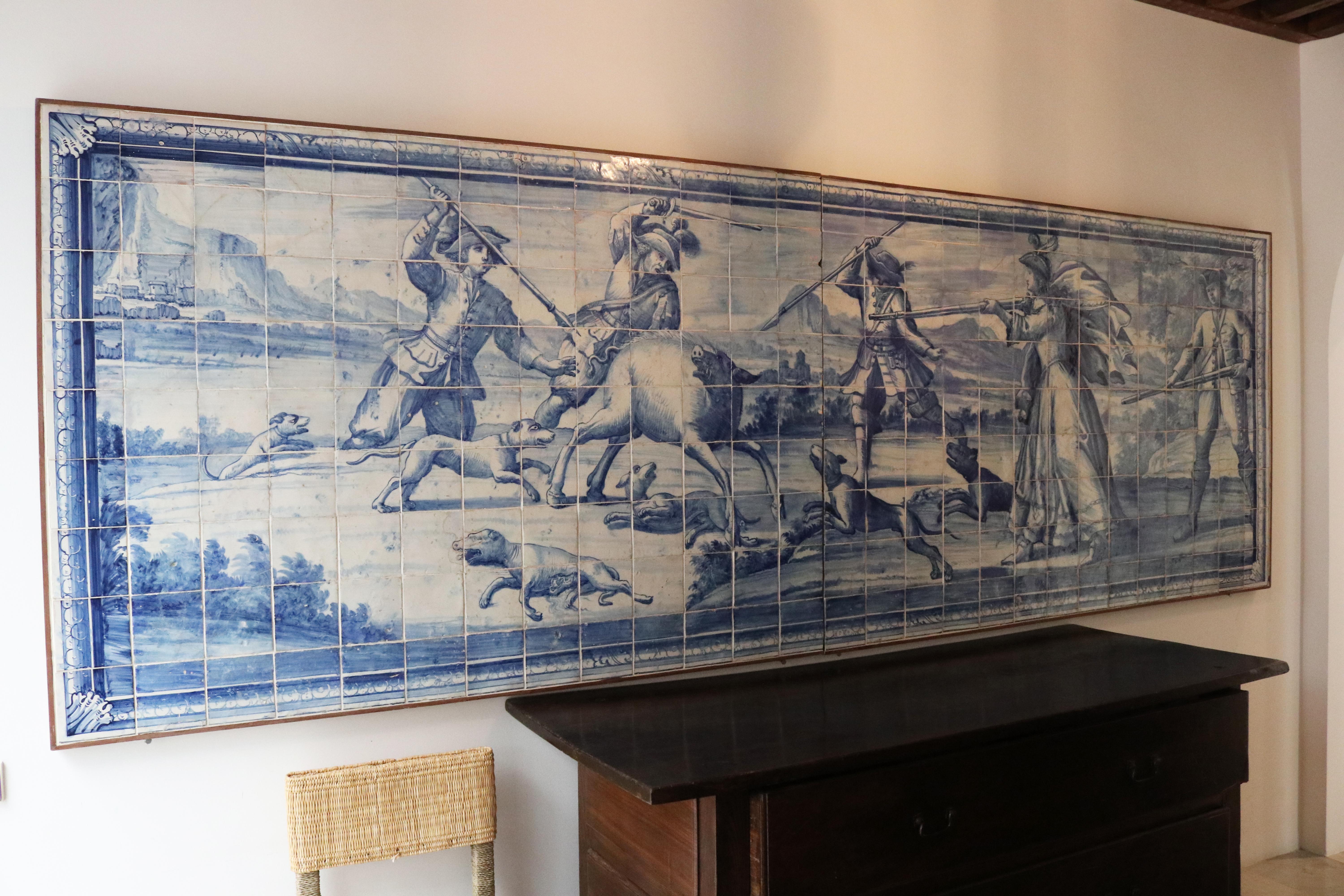 Large 18th century Portuguese panel in blue and white glazed ceramic, representing a hunting scene composed of five persons dressed in period costumes, dogs and a wild boar. 



