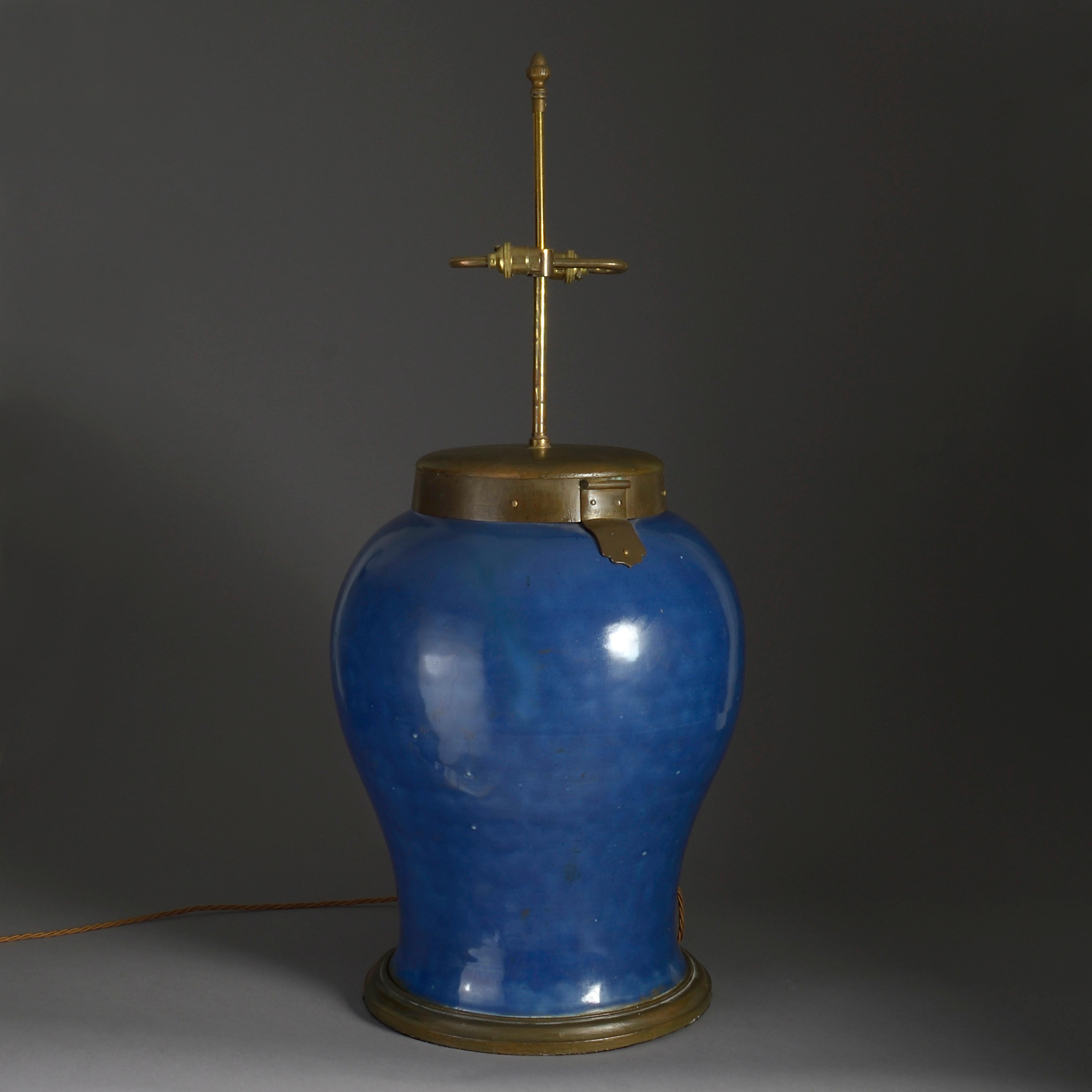 A large powder blue glazed vase, of baluster form, having a later bronzed cap and circular base, and wired as a table lamp.