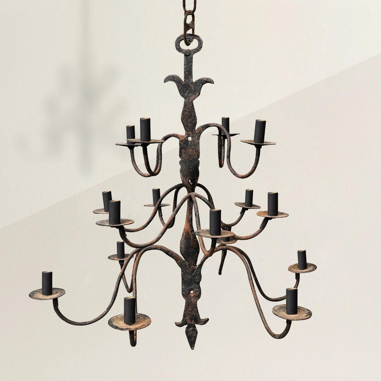 A remarkable 18th century Quebecois wrought-iron chandelier with sixteen scrolling arms in three tiers and supported by a twisted body with stylized floral ends and a large oval ring for hanging. Found in Quebec.