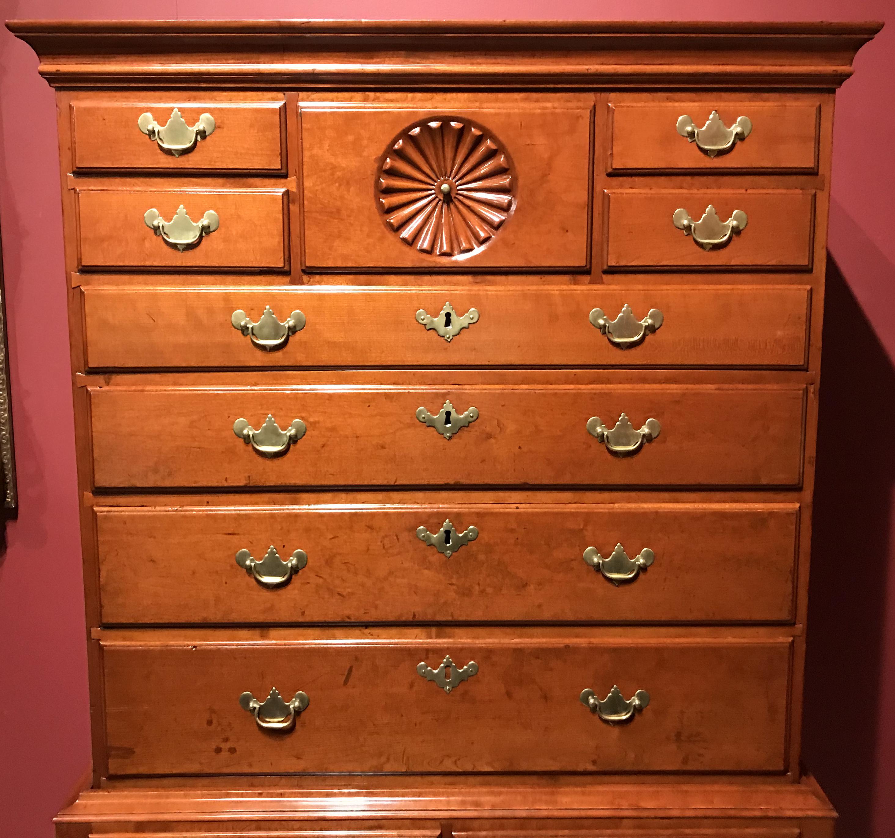 18th century Queen Anne cherrywood highboy of probable Connecticut origin. Upper case with a central pinwheel-carved drawer flanked by stacks of two narrow drawers all-over four graduated full-width drawers. Lower case with two short drawers over