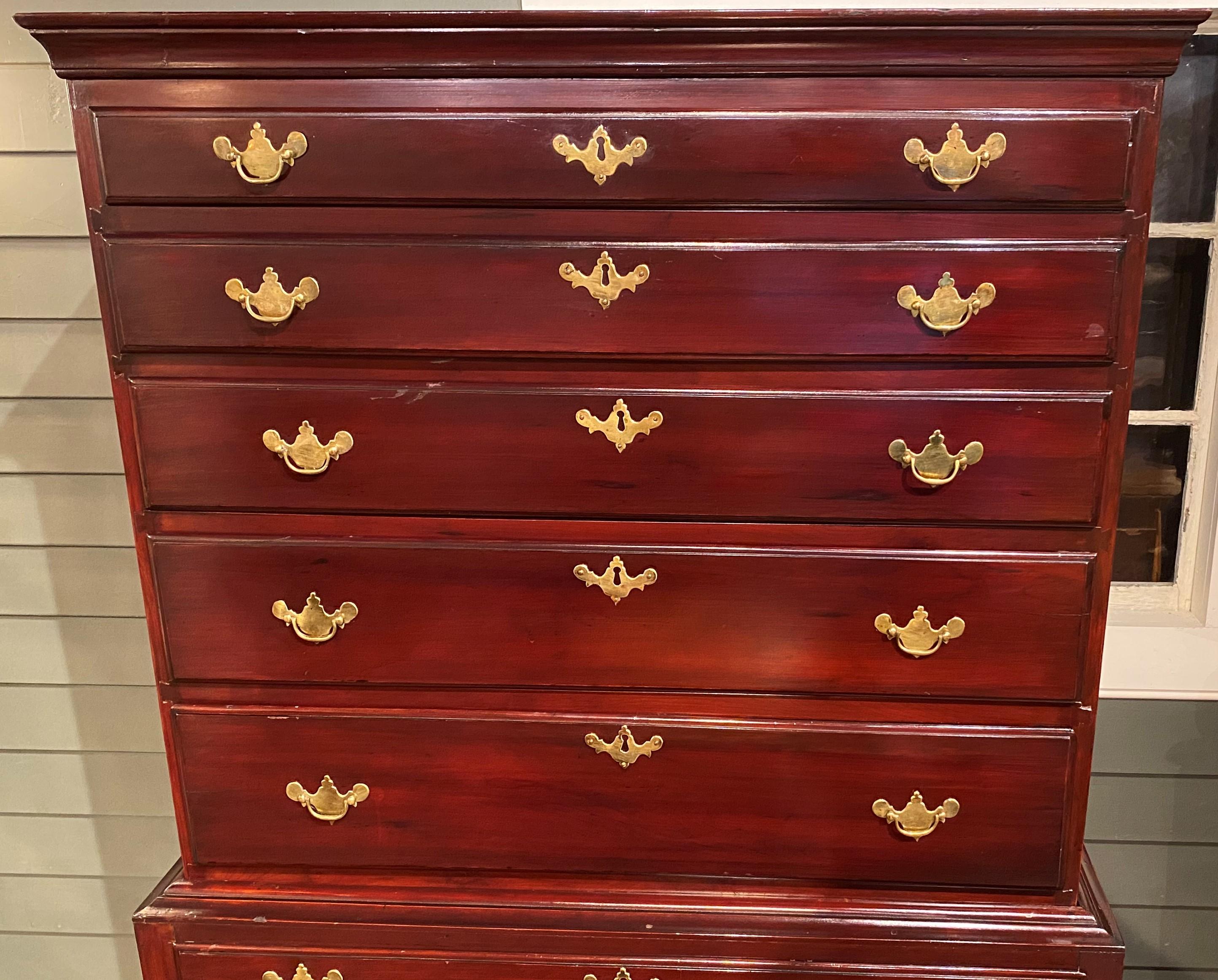 A beautiful Queen Anne cherry wood two part highboy with a mahoganized finish, with a molded cornice surmounting an upper case with five graduated drawers, over a lower case with a single long drawer over three fitted drawers, the central of which