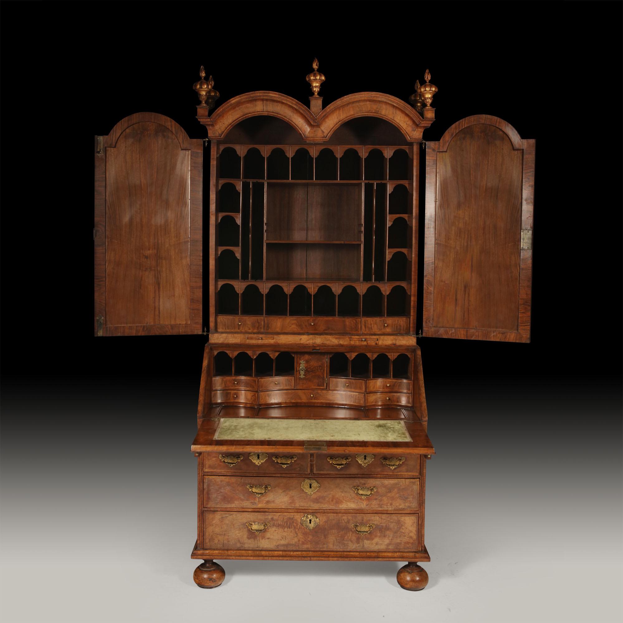 A Queen Anne fully fitted figured-walnut double dome bureau bookcase, circa 1710

The moulded 'double domed' pediment above a pair of mirror panelled doors, opens to a fully fitted divided interior incorporating small feather-banded figured walnut