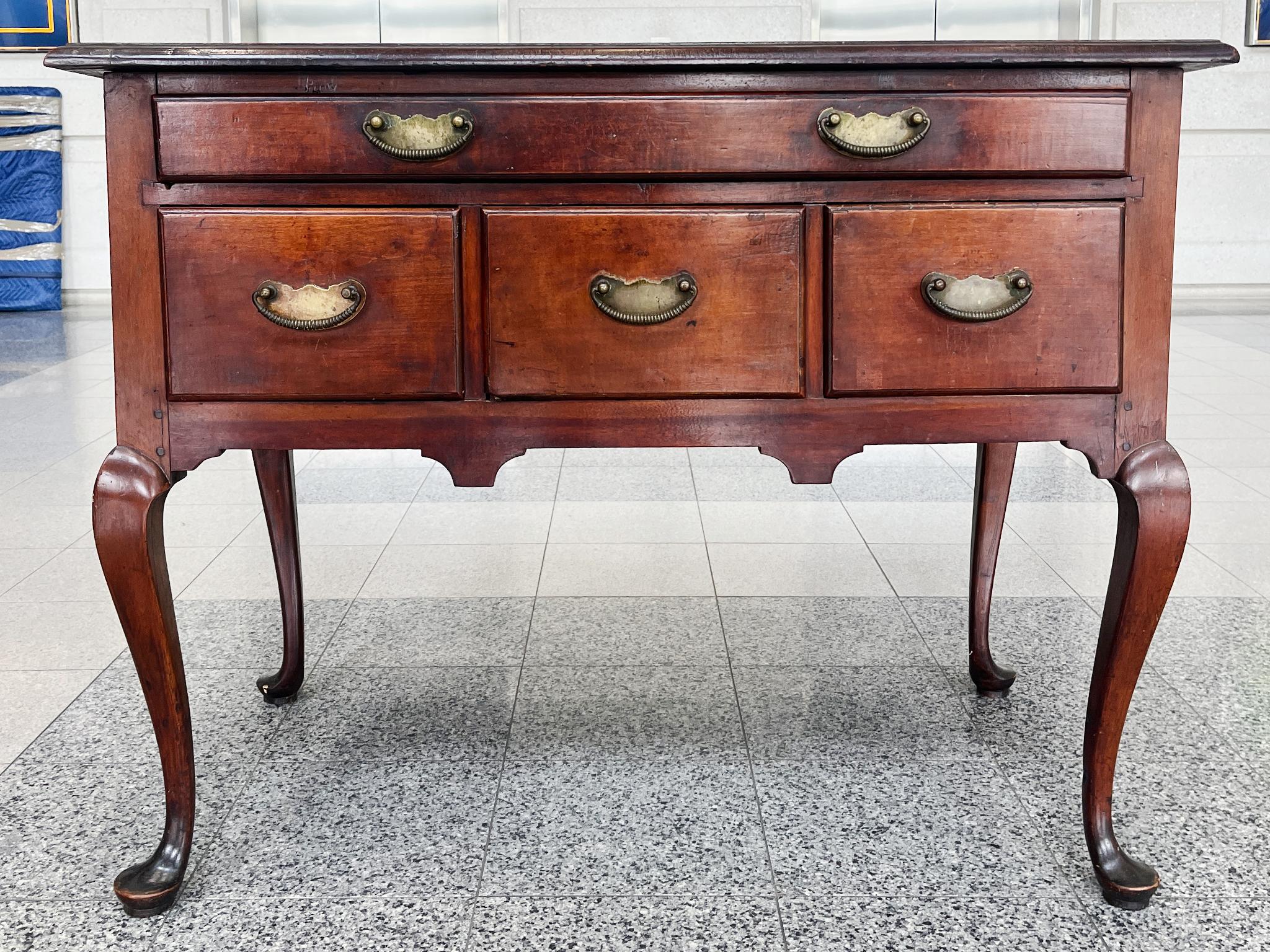 Handcrafted in the 18th Century, this Queen Anne lowboy is mahogany with brass hardware. The design is one of restrained elegance, typifying the Queen Anne style with its focus on clean lines and simplified forms. The chest has ample storage space