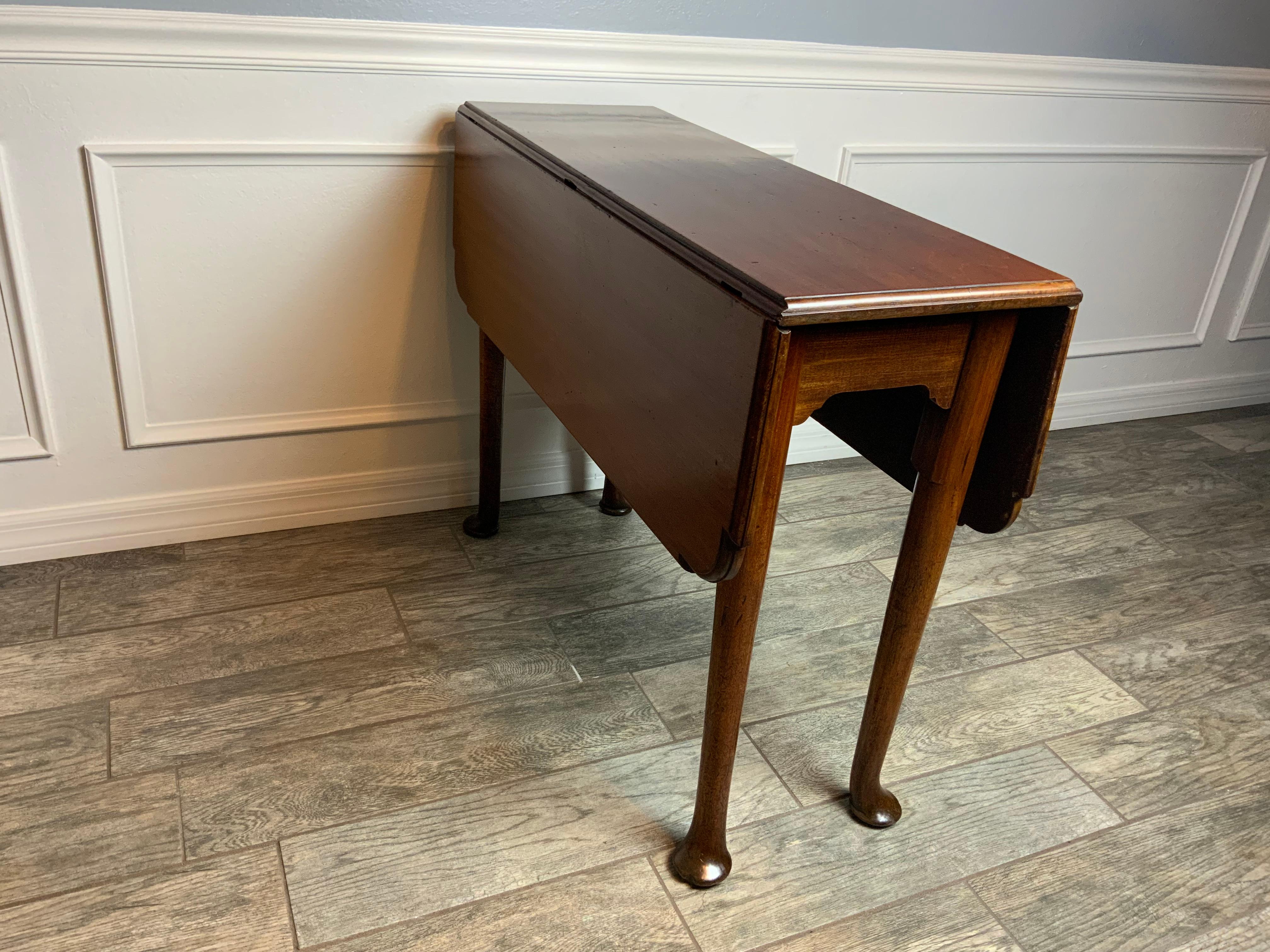 A very nice small size 18th Century Mahogany Queen Anne Pembroke table resting on tapered straight legs ending in nice wide pad feet.  Most of these Queen Anne drop leaf tables commonly seen are oval or round in shape.   This one has rectangular