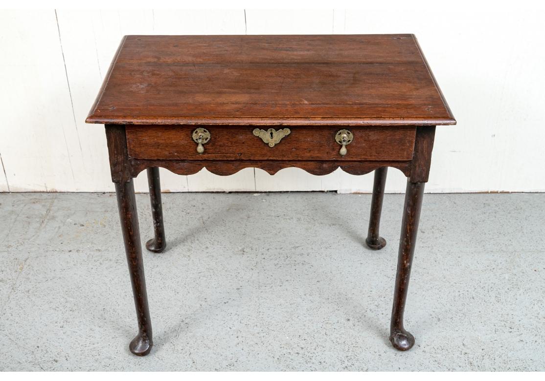 A handsome and early Queen Ann style Lowboy Table with a fine form and age patina. An 18th century dressing table with a single drawer having an engraved escutcheon plate, brass teardrop pulls, scalloped apron and resting upon gently tapering legs