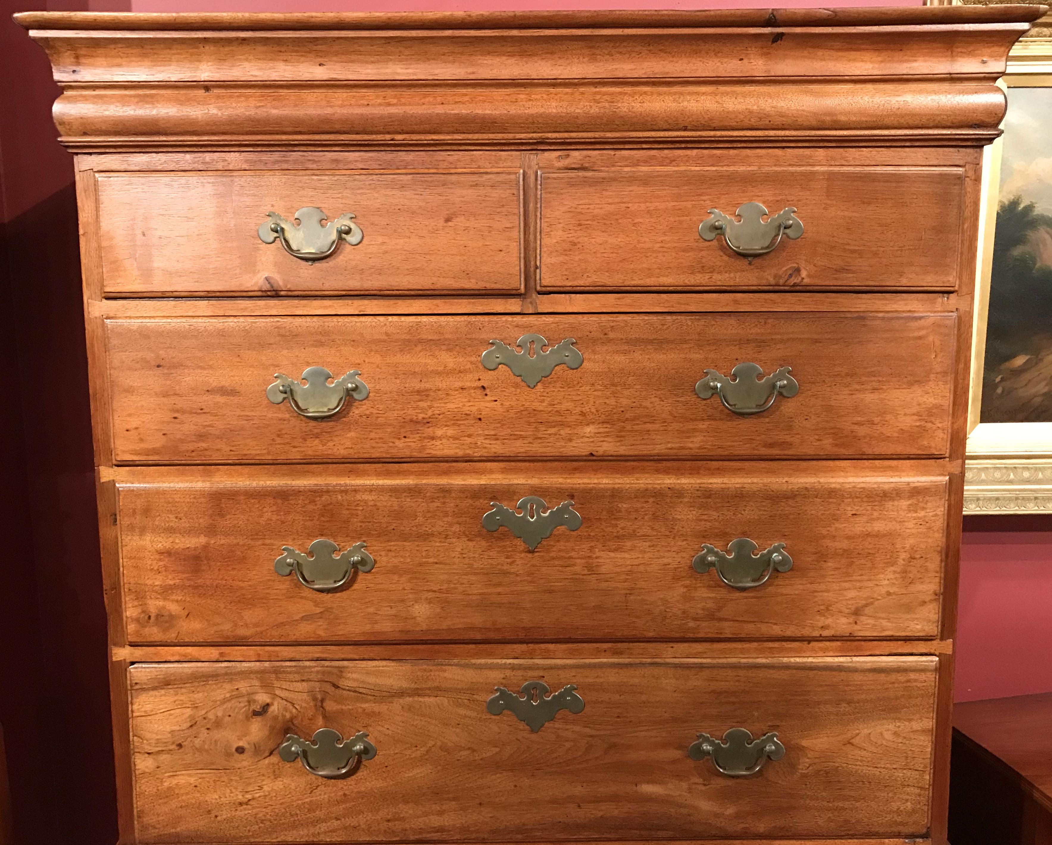 A fine example of a Queen Anne two part flat top walnut highboy, its upper case with a molded cornice surmounting a two over three drawer configuration with what appear to be the original batwing brasses, and a lower case with one long drawer over