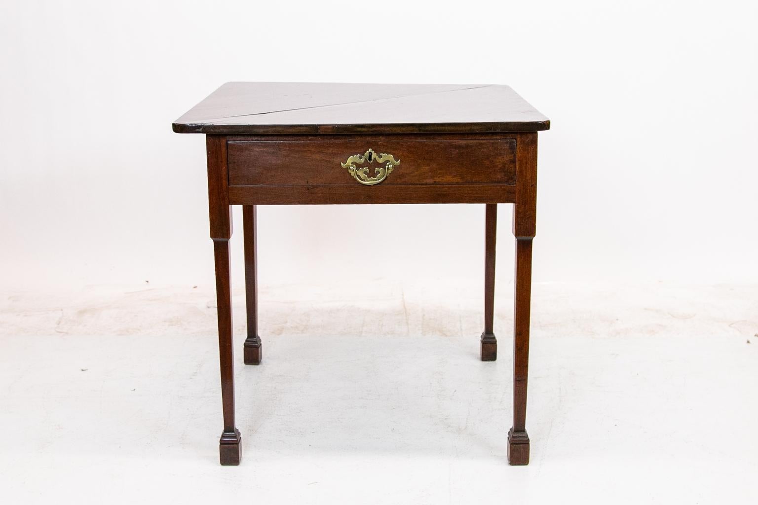 18th century rare handkerchief table has a triangular drop leaf and pie shaped hinged drawer. It sits on tapered legs terminating in Marlborough feet.