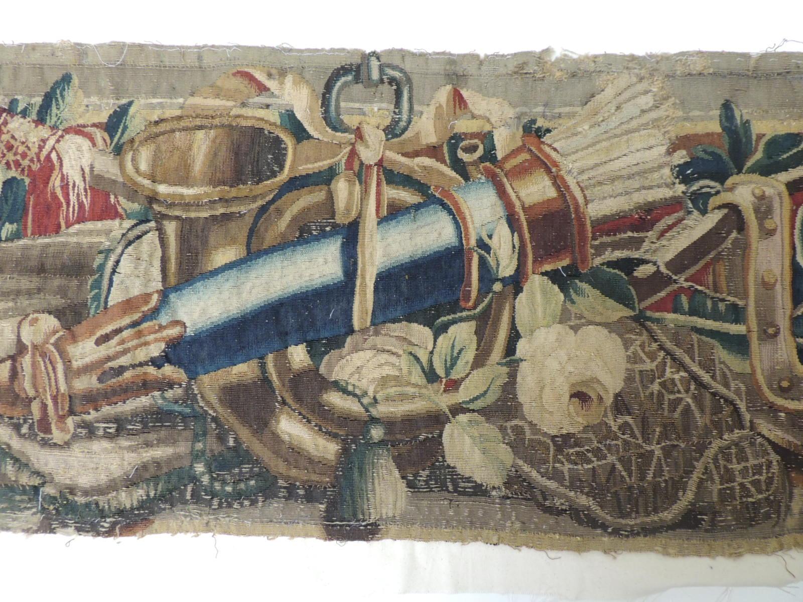 18th century red and blue Aubusson tapestry panel.
This fragment depicts archery and hunting instruments on top of a cushion.
Tassels, flowers cups and vines are depicted throughout. In shades of gold, green, blue, red, yellow and brown.
Size: 12